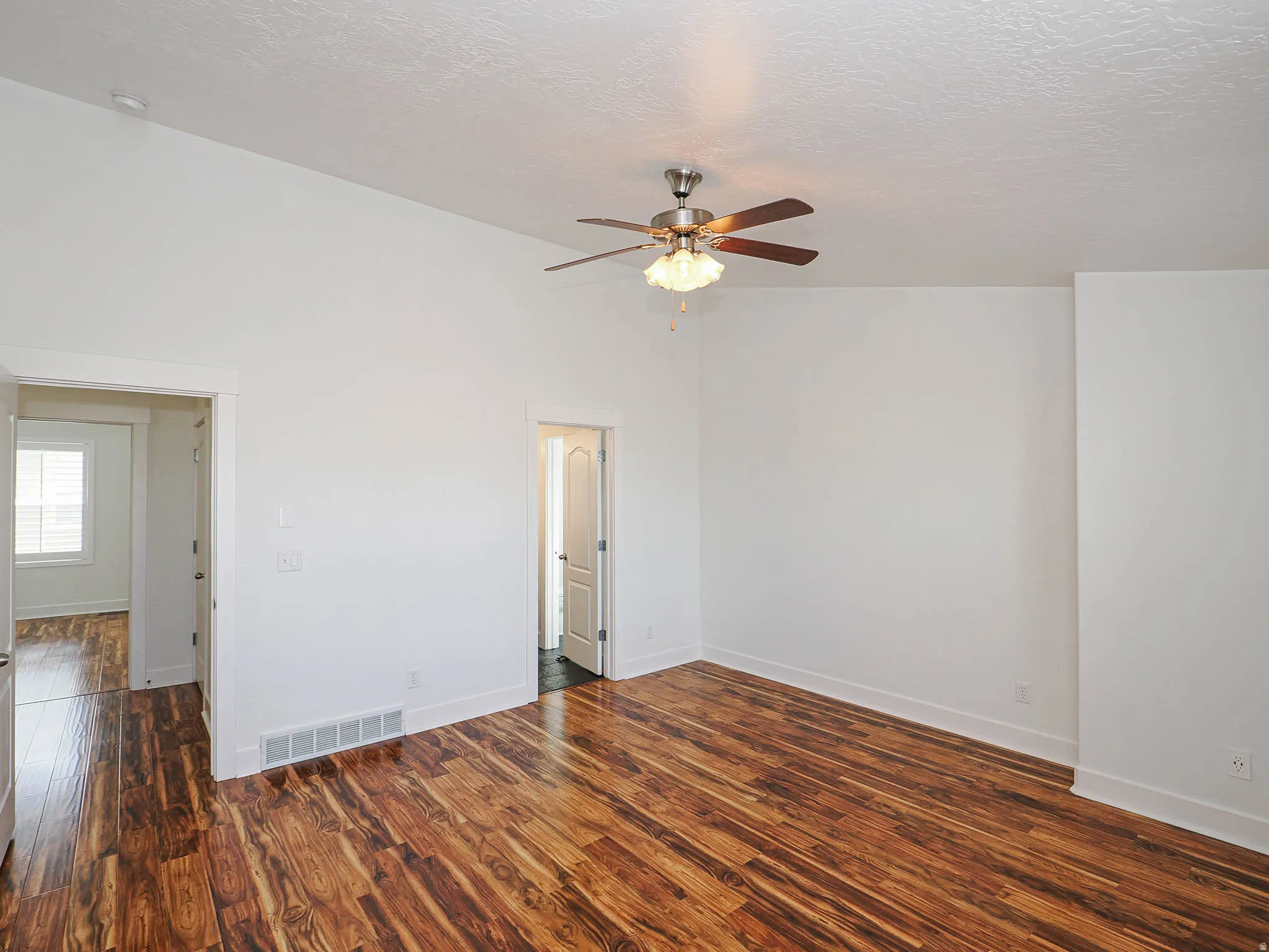 Spare room featuring dark wood-style floors, a textured ceiling, and ceiling fan