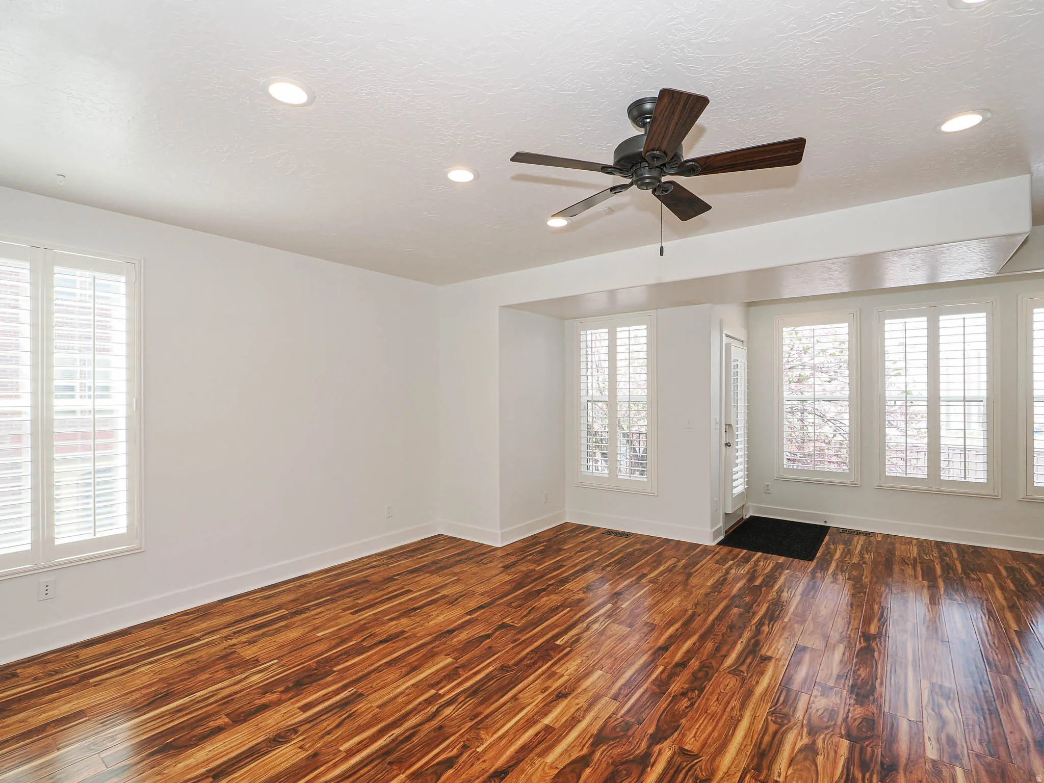 Unfurnished living room with dark wood-type flooring, ceiling fan, plenty of natural light, a textured ceiling, and recessed lighting