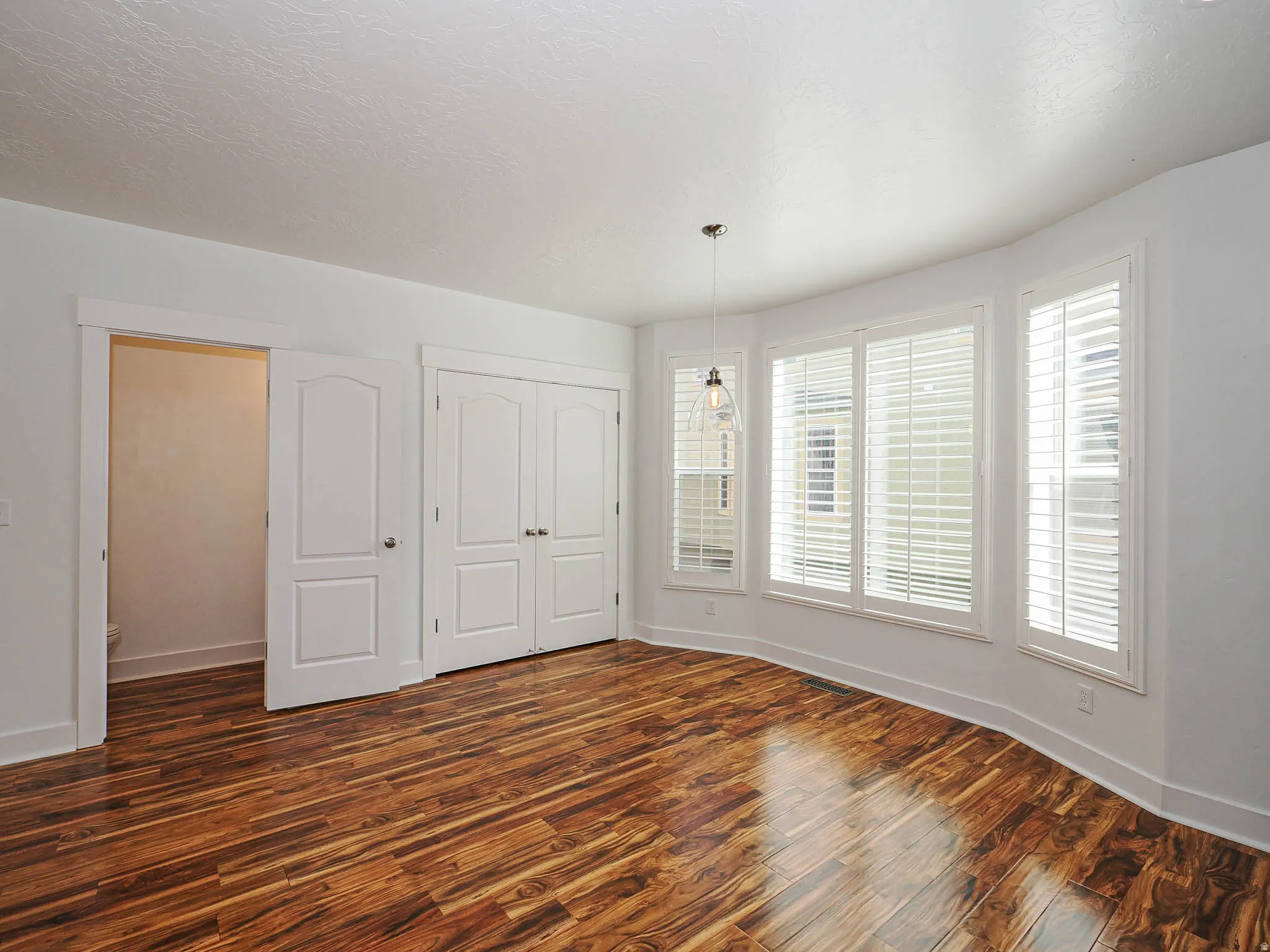 Unfurnished bedroom featuring dark wood-type flooring, a closet, and a textured ceiling