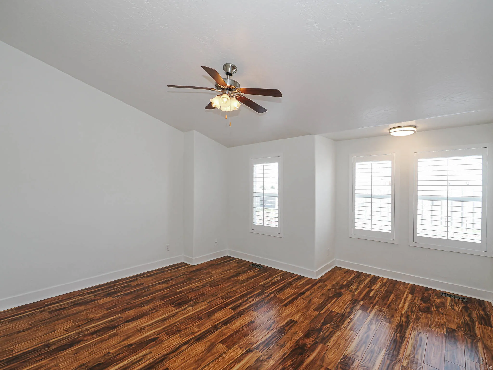 Spare room featuring dark wood-style floors and ceiling fan