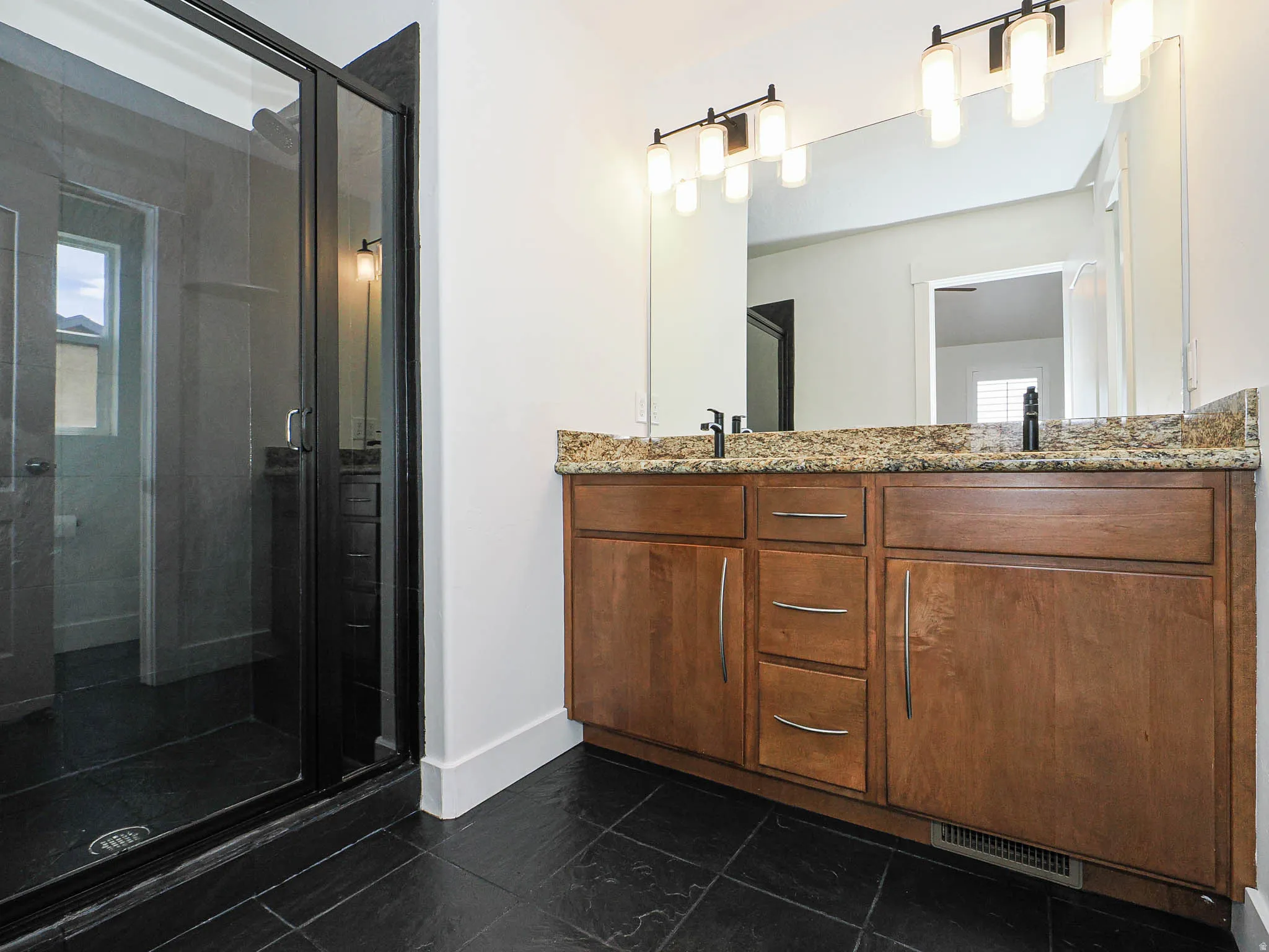Bathroom featuring double vanity, a shower stall, and healthy amount of natural light