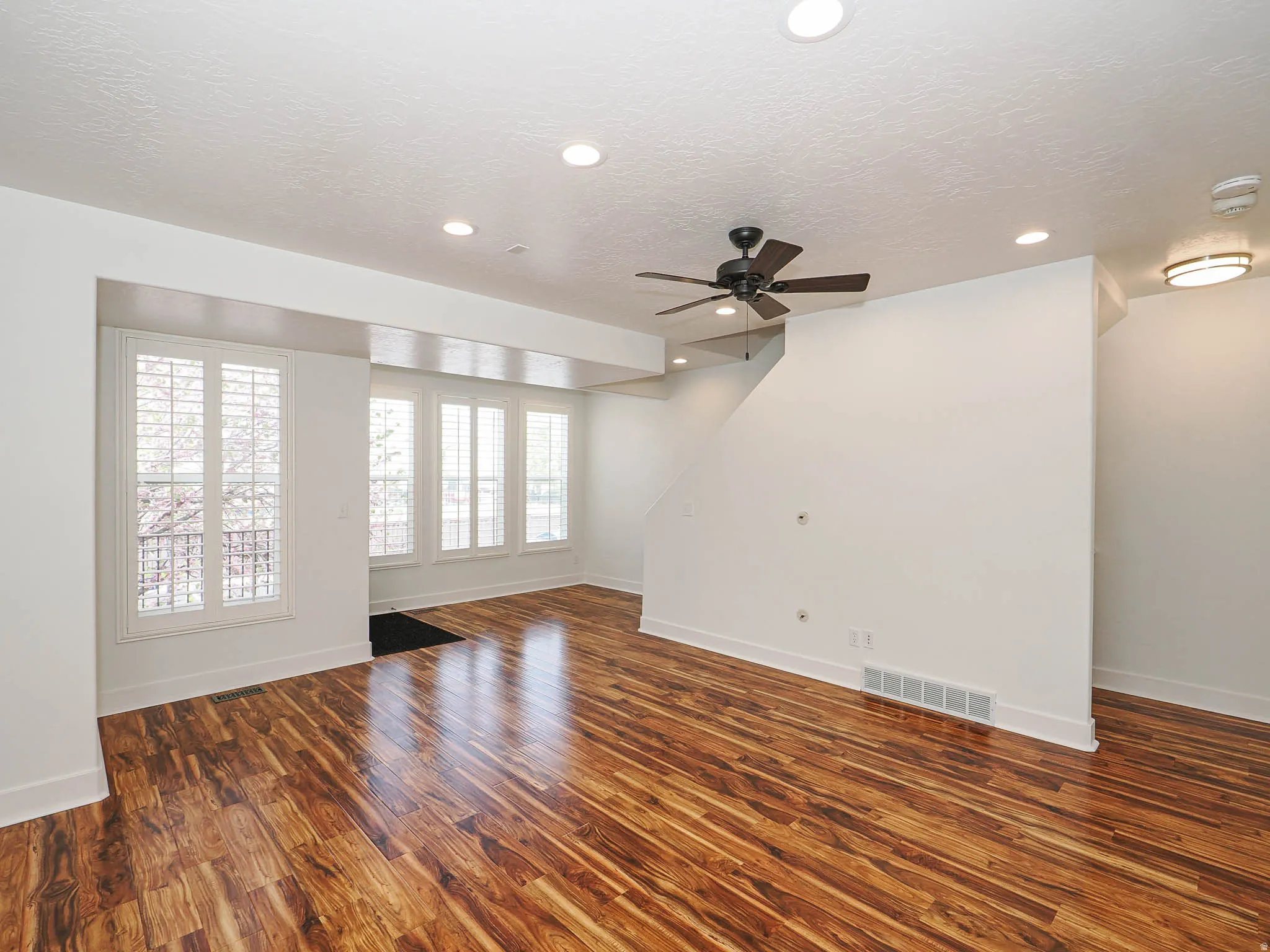Unfurnished living room featuring a ceiling fan, dark wood-type flooring, recessed lighting, and a textured ceiling