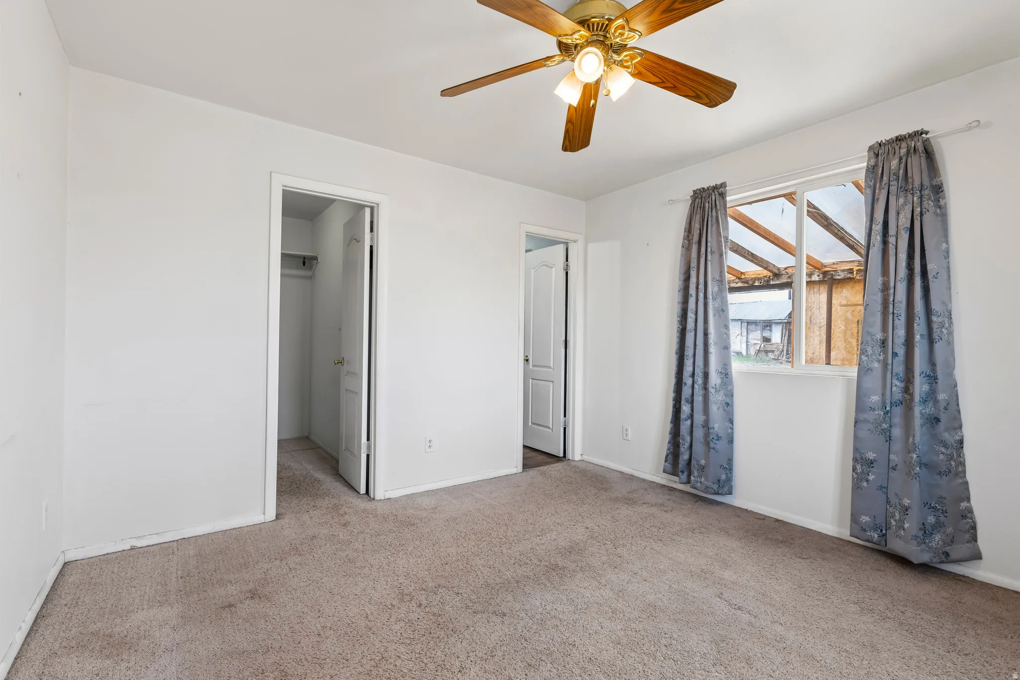 Unfurnished bedroom with carpet, ceiling fan, and a walk in closet