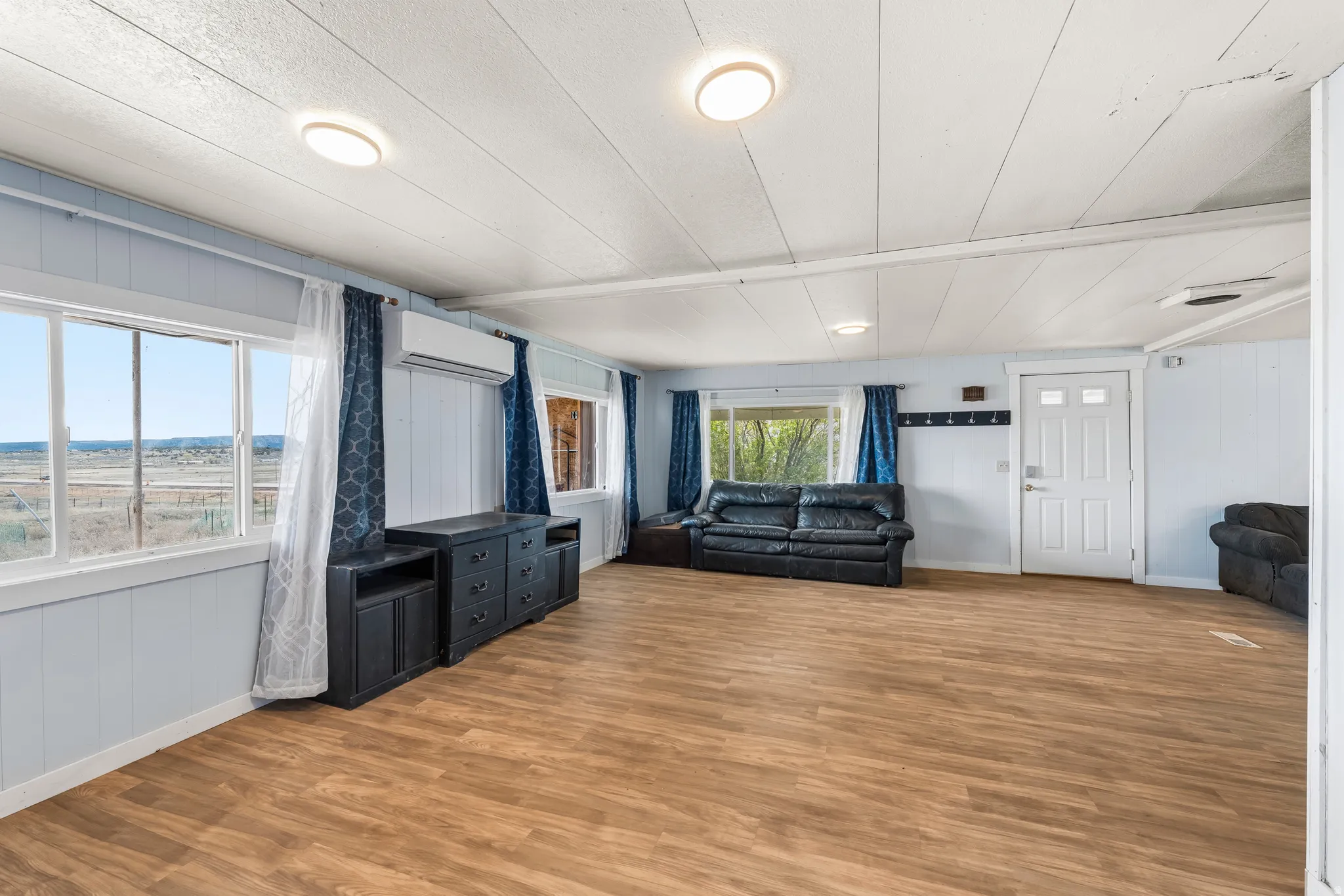 Living room with light wood finished floors, wood walls, and a decorative wall