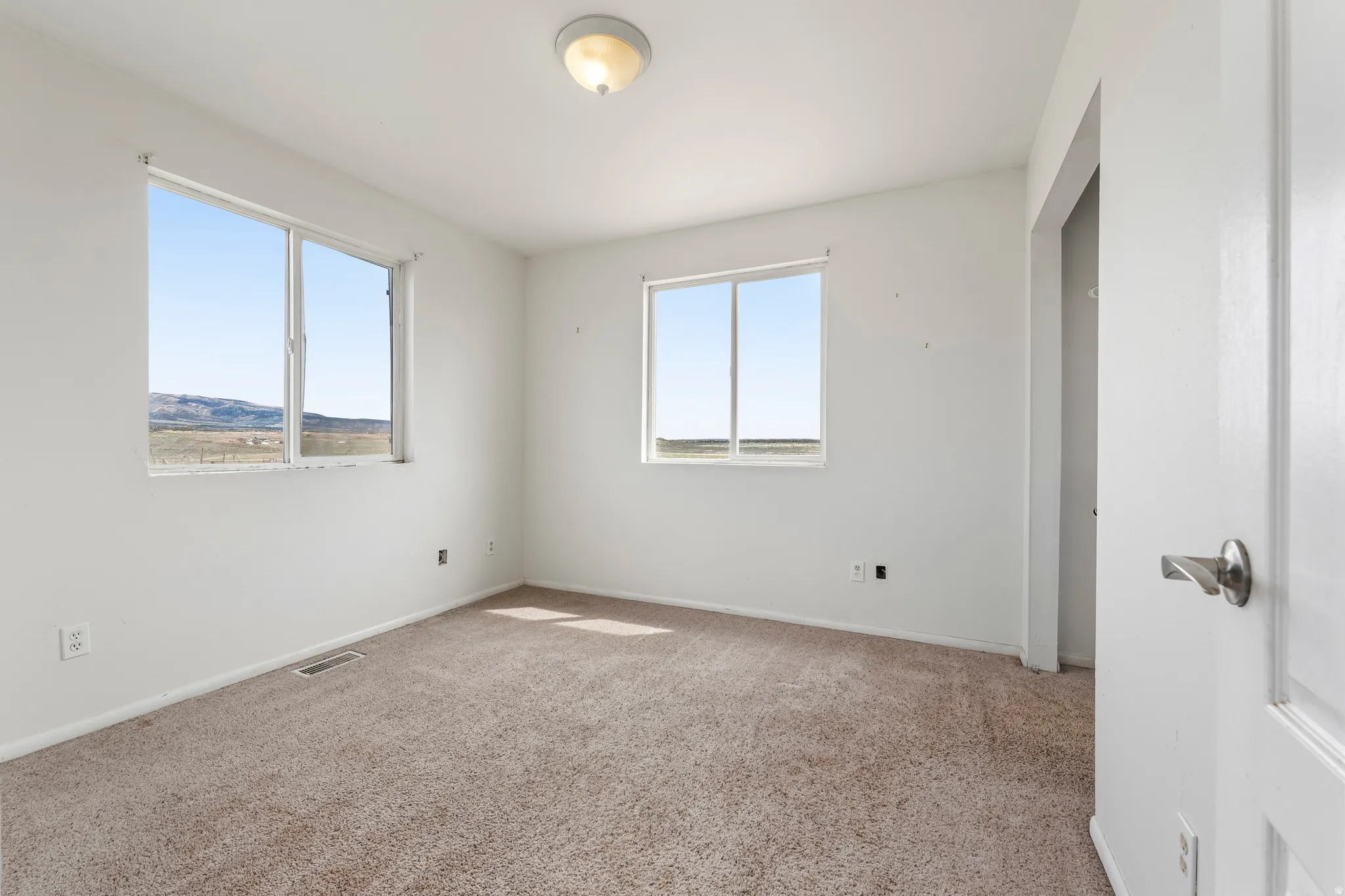 Unfurnished bedroom with light carpet and baseboards