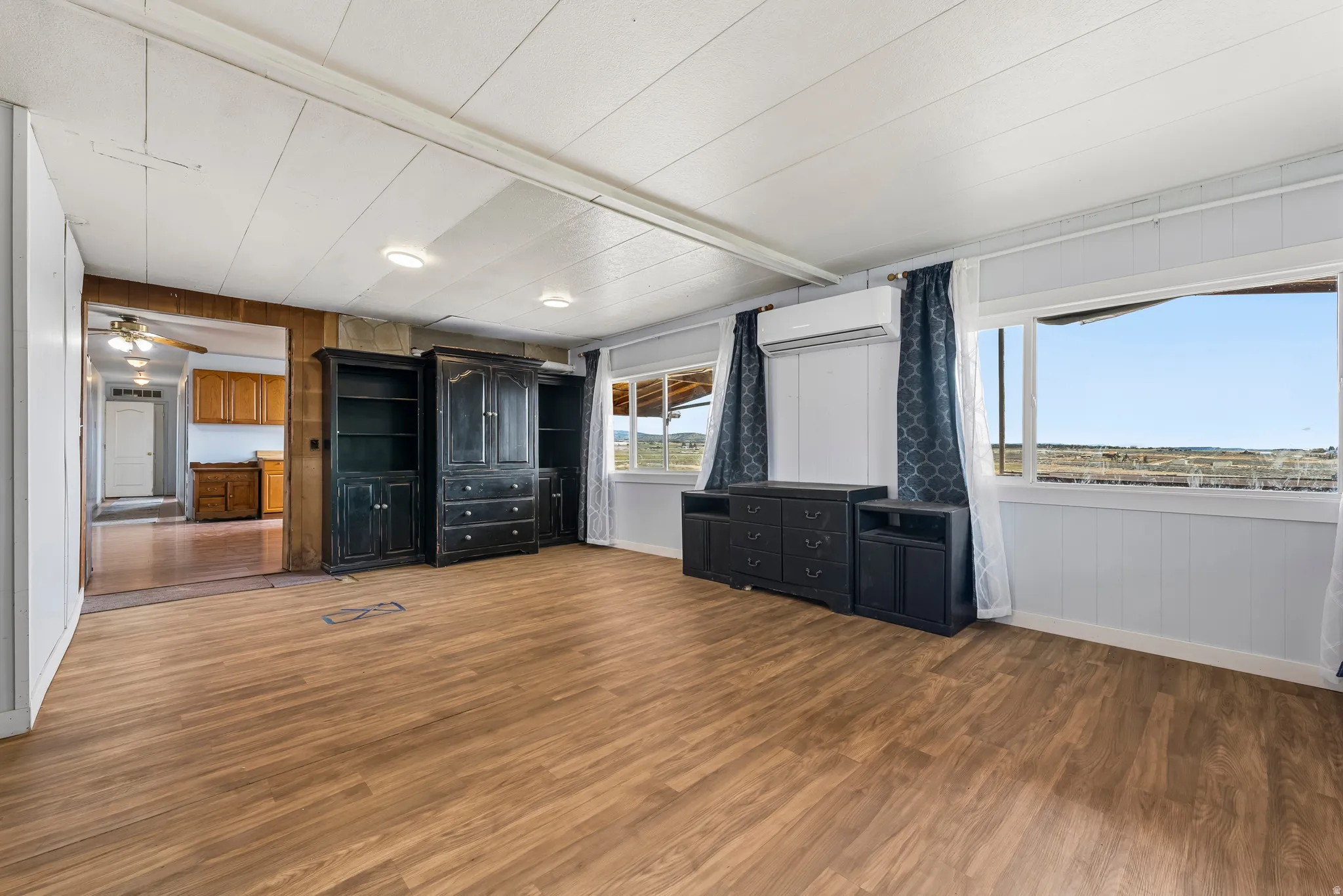Unfurnished bedroom with wooden walls, dark wood-style flooring, and a mini split for heating / cooling