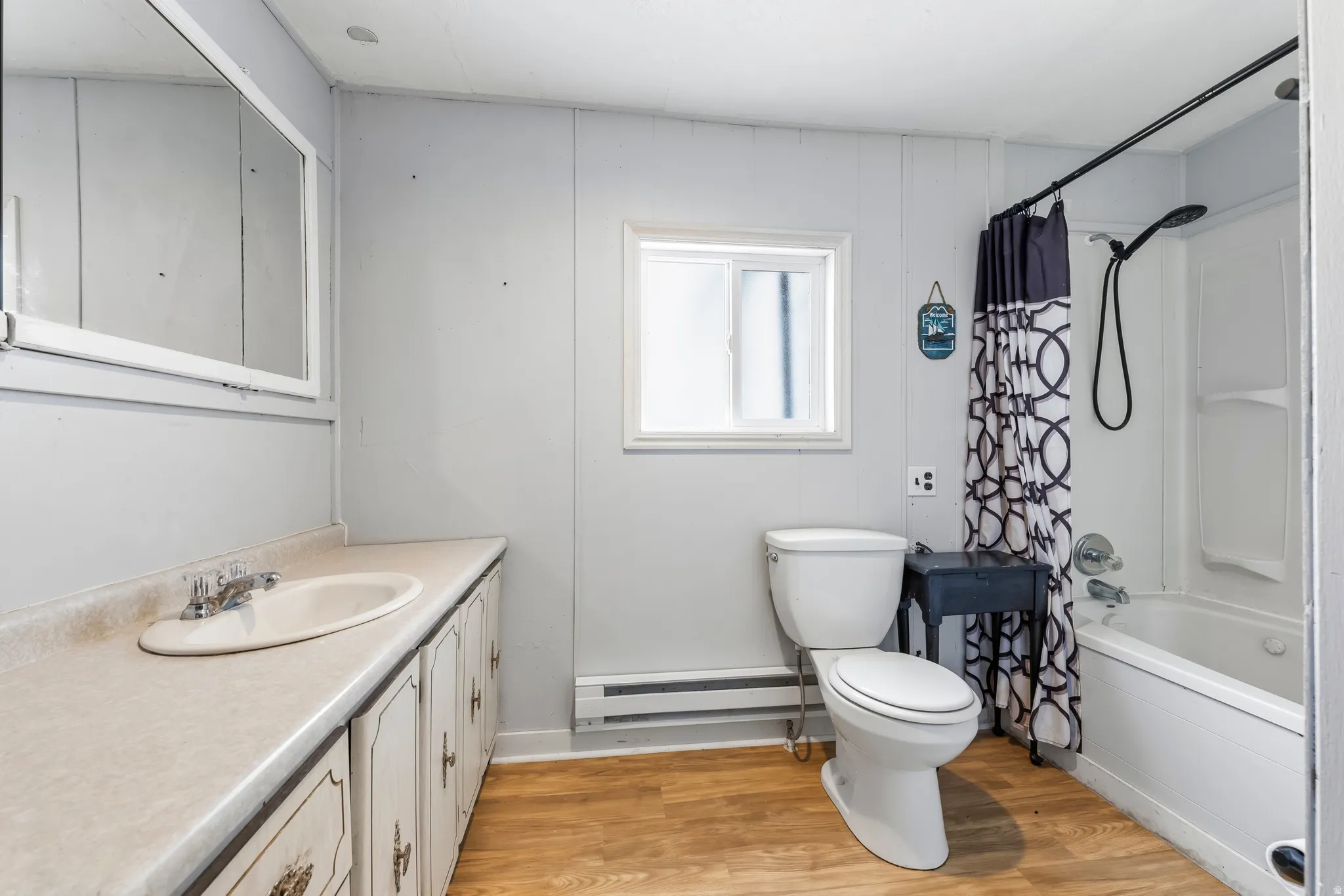 Bathroom featuring light wood-style floors, vanity, a baseboard radiator, and shower / bath combination with curtain