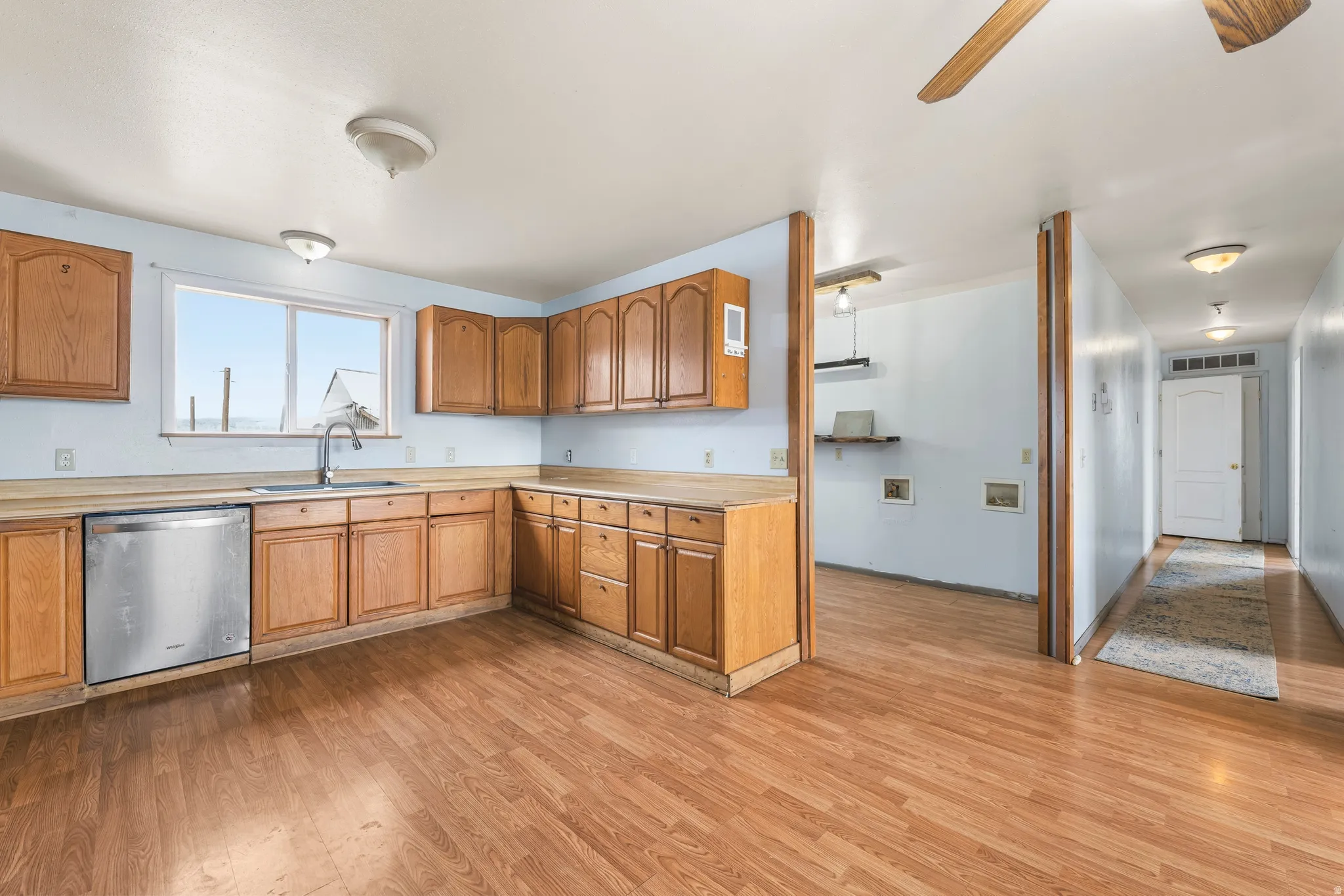 Kitchen featuring light countertops, dishwasher, light wood-style flooring, and ceiling fan