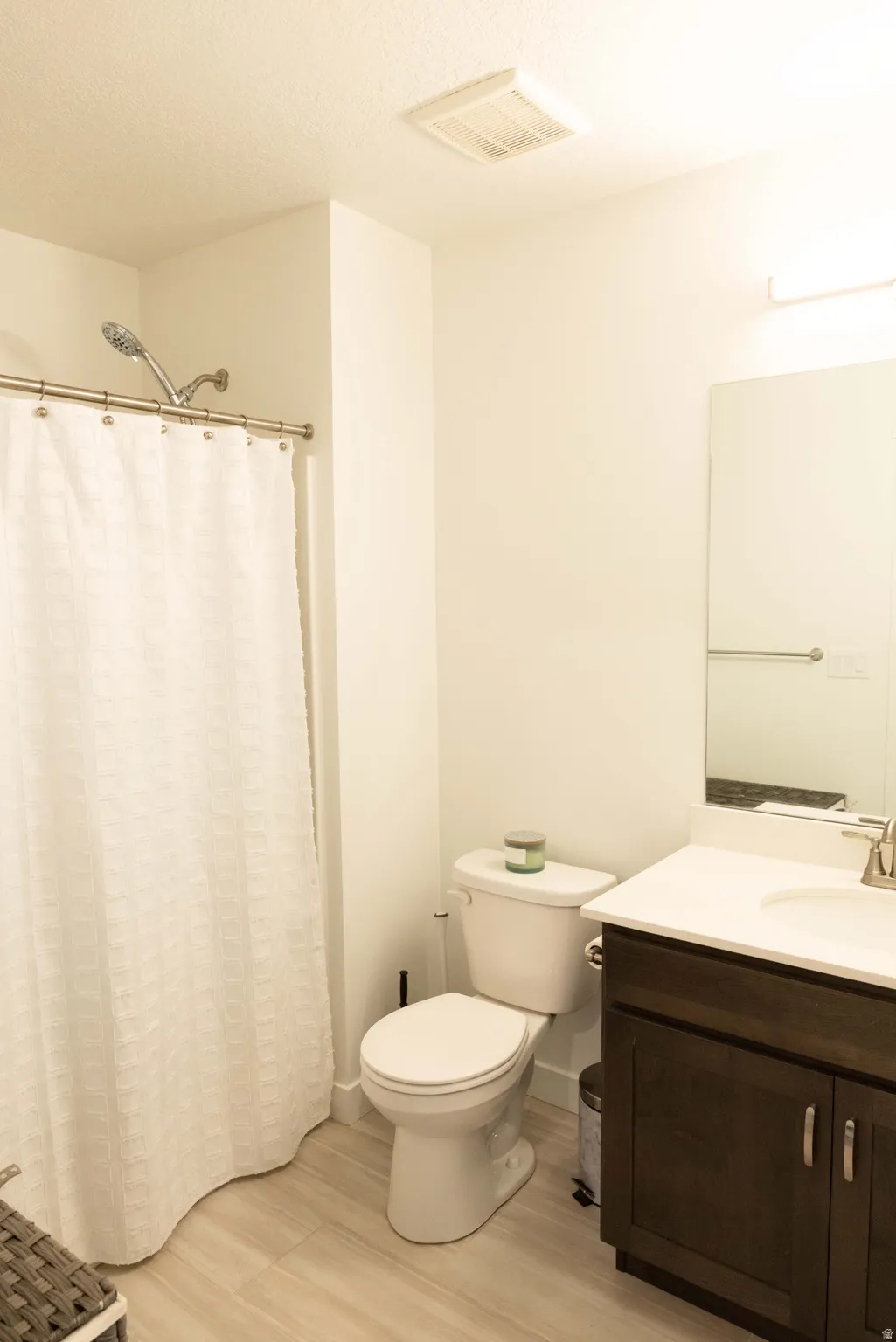 Bathroom featuring vanity, curtained shower, light wood-style flooring, and a textured ceiling
