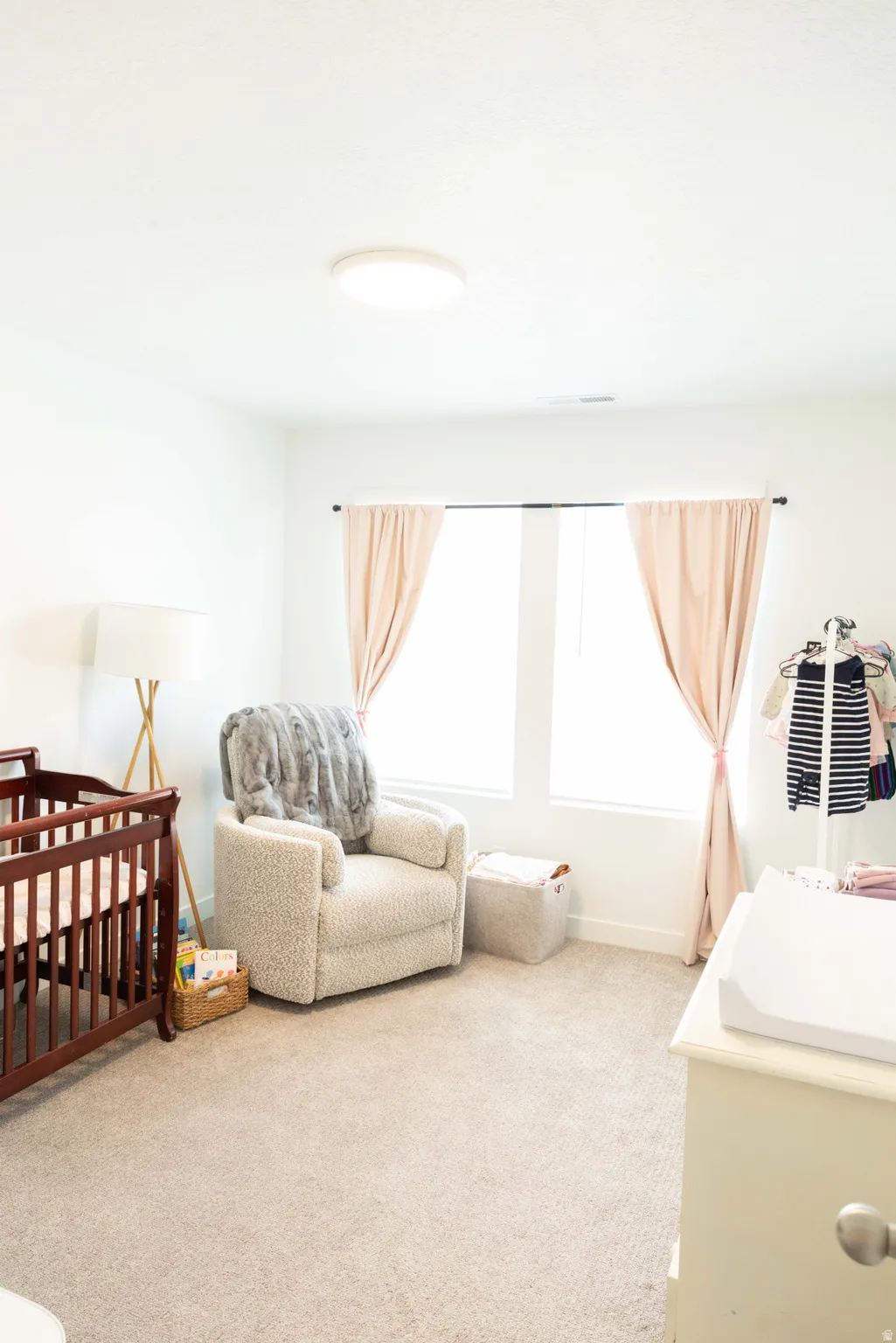 Bedroom featuring light carpet and a crib
