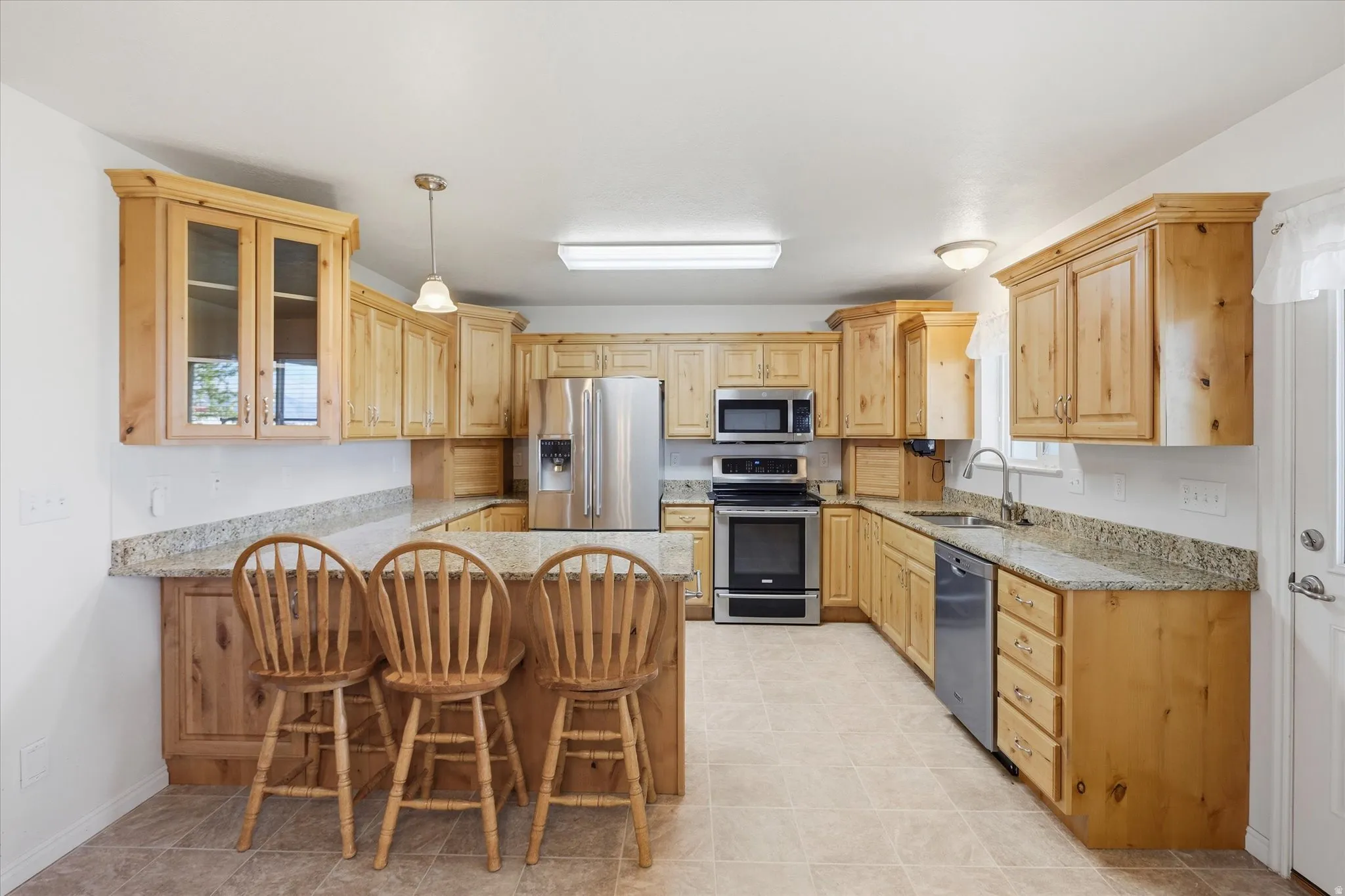 Kitchen with light stone counters, a breakfast bar, and a peninsula