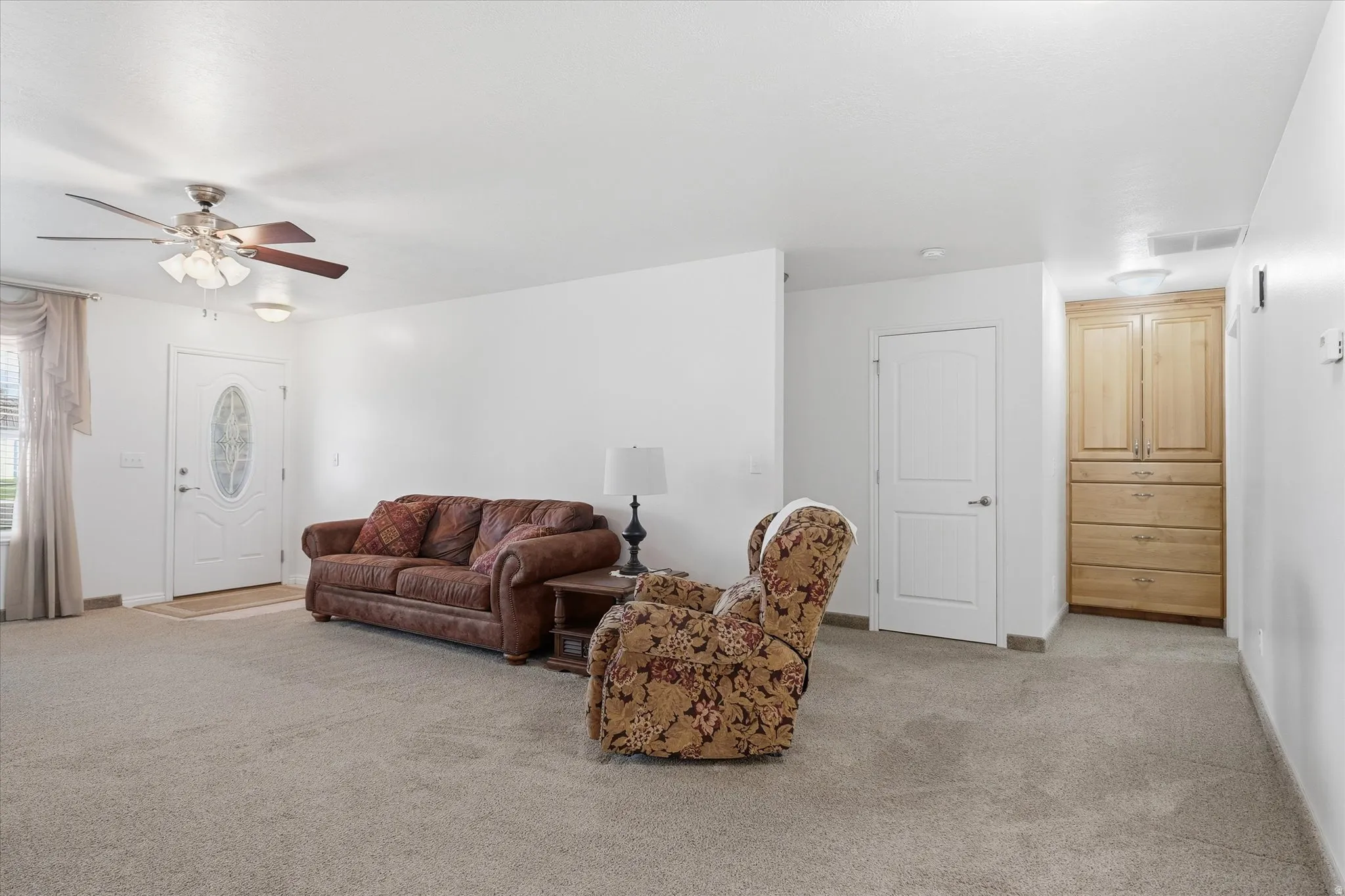 Living area with light carpet and ceiling fan