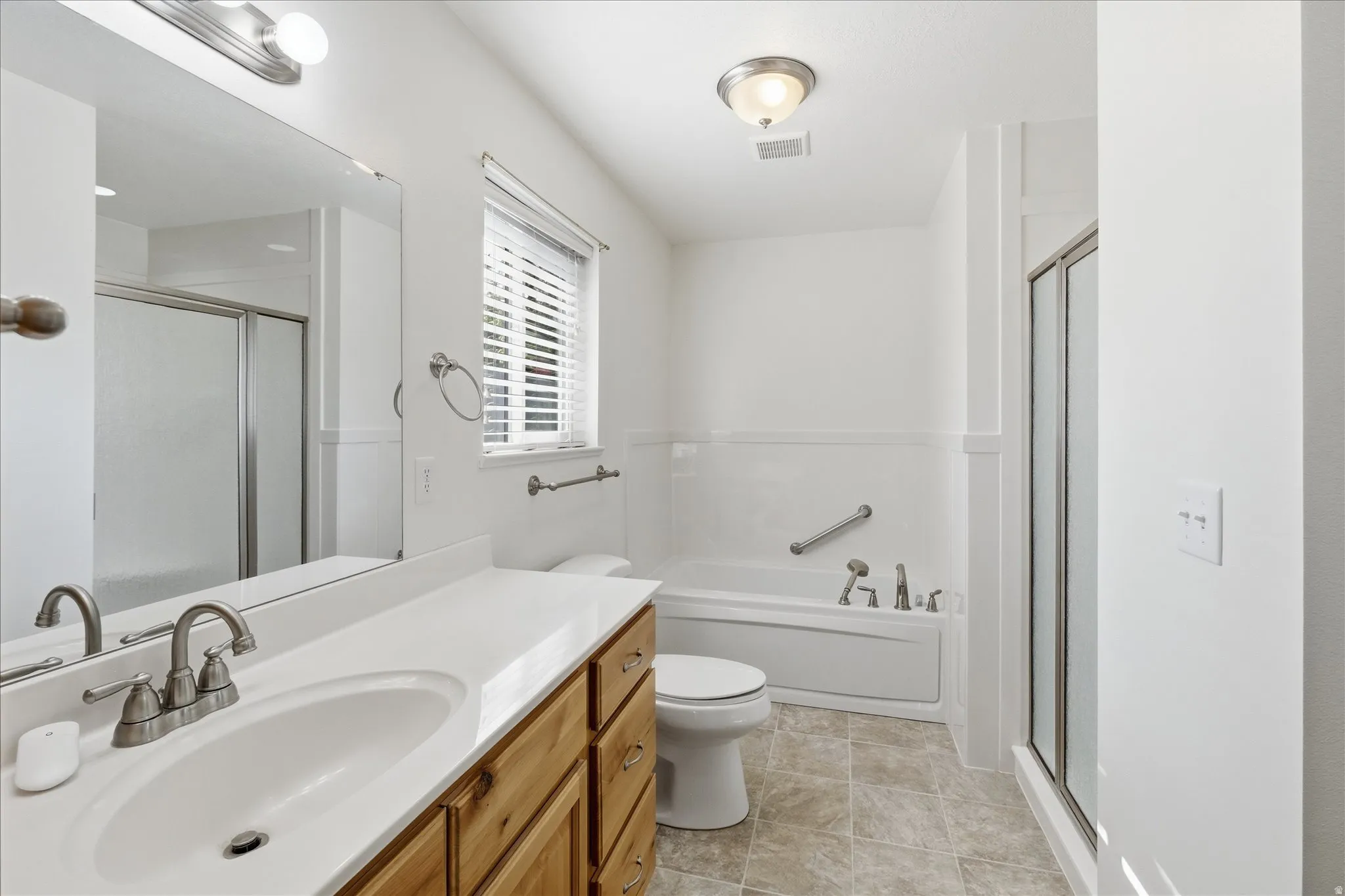 Primary bath featuring vanity, soaker tub, a shower stall, and light tile patterned floors