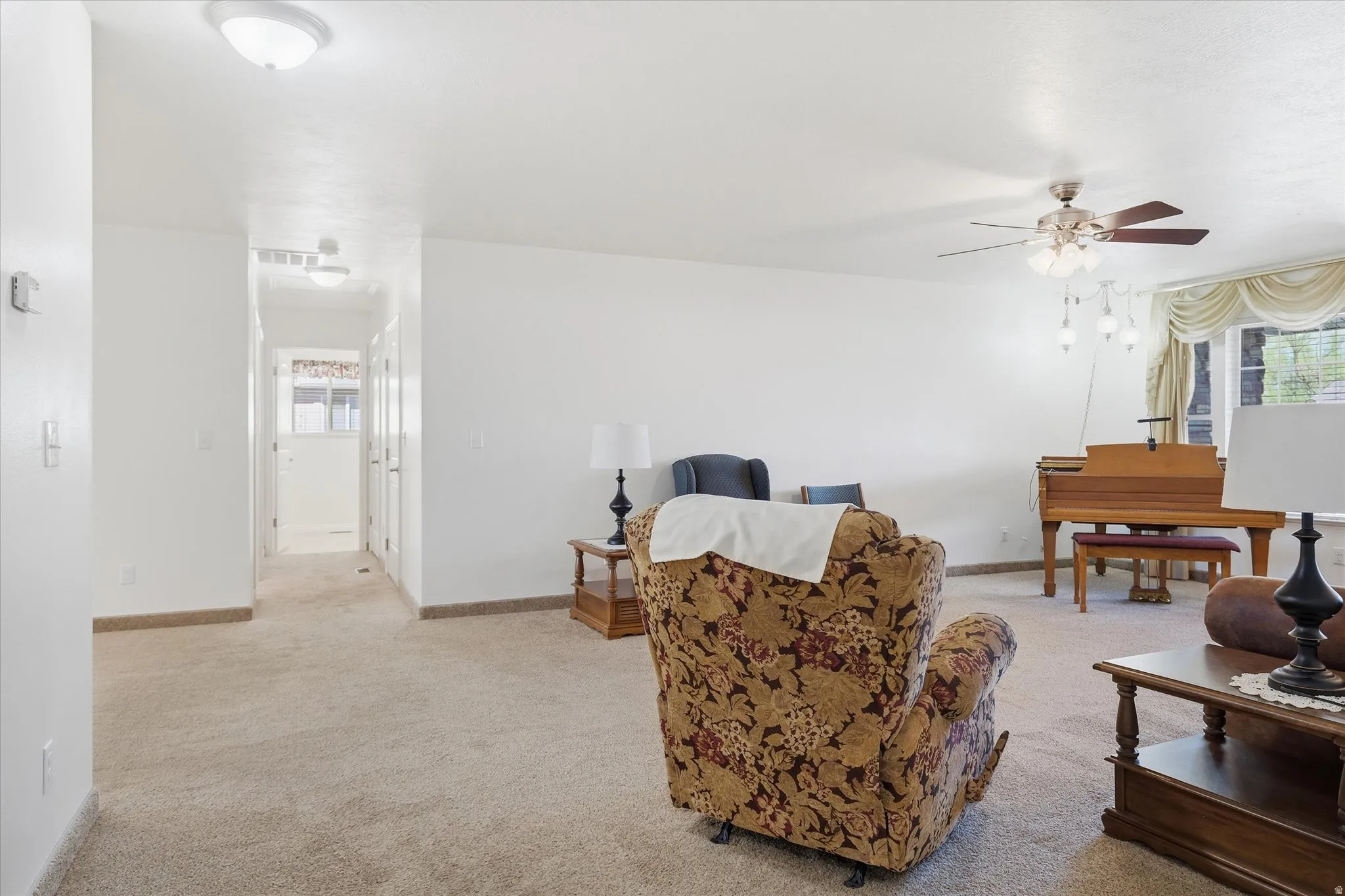 Living area featuring light colored carpet and a ceiling fan