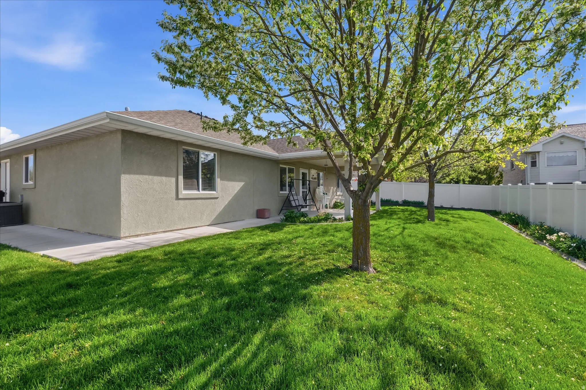 Back of property with stucco siding, a fenced backyard, a patio area, and a shingled roof