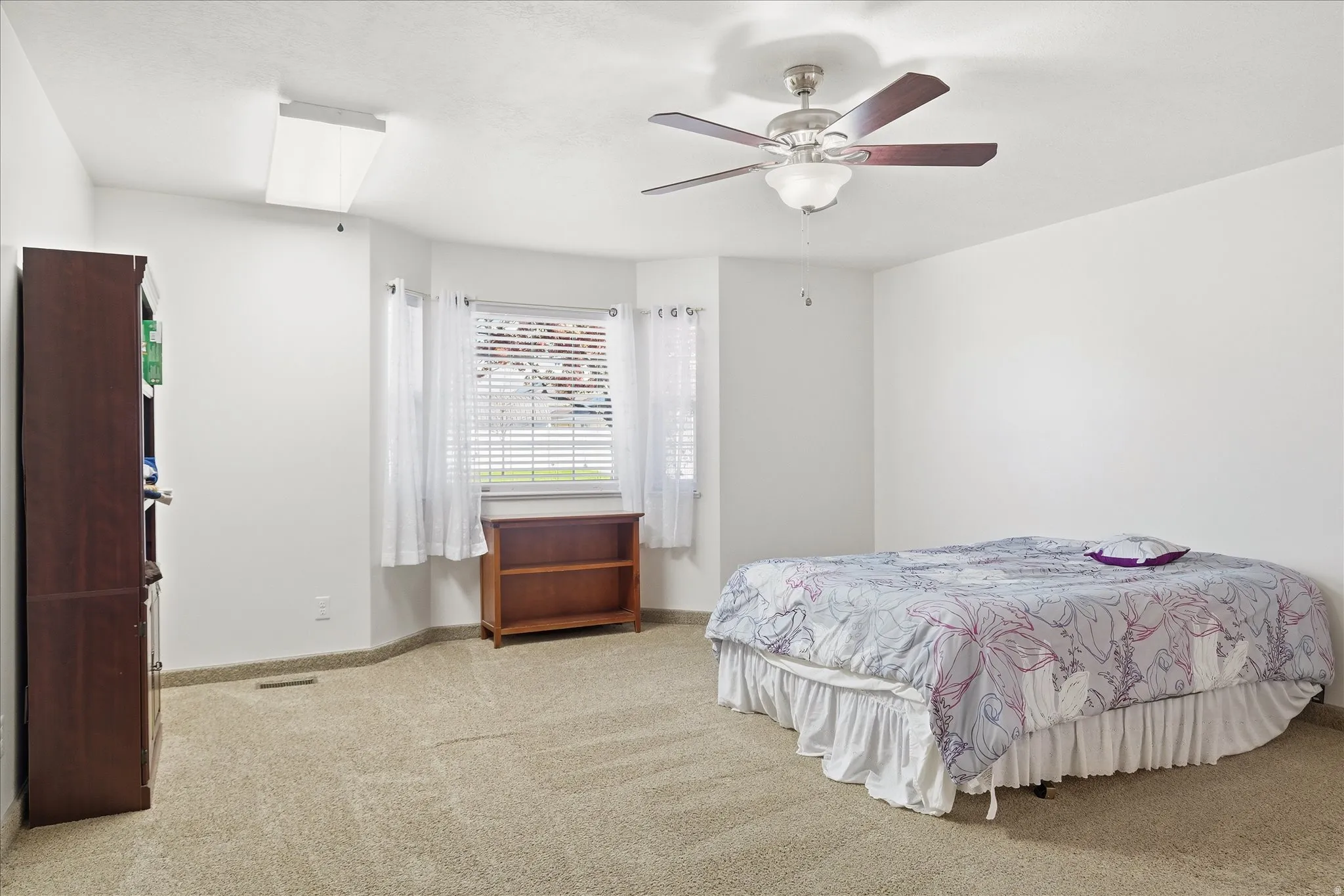 Primary bedroom with light colored carpet and a ceiling fan