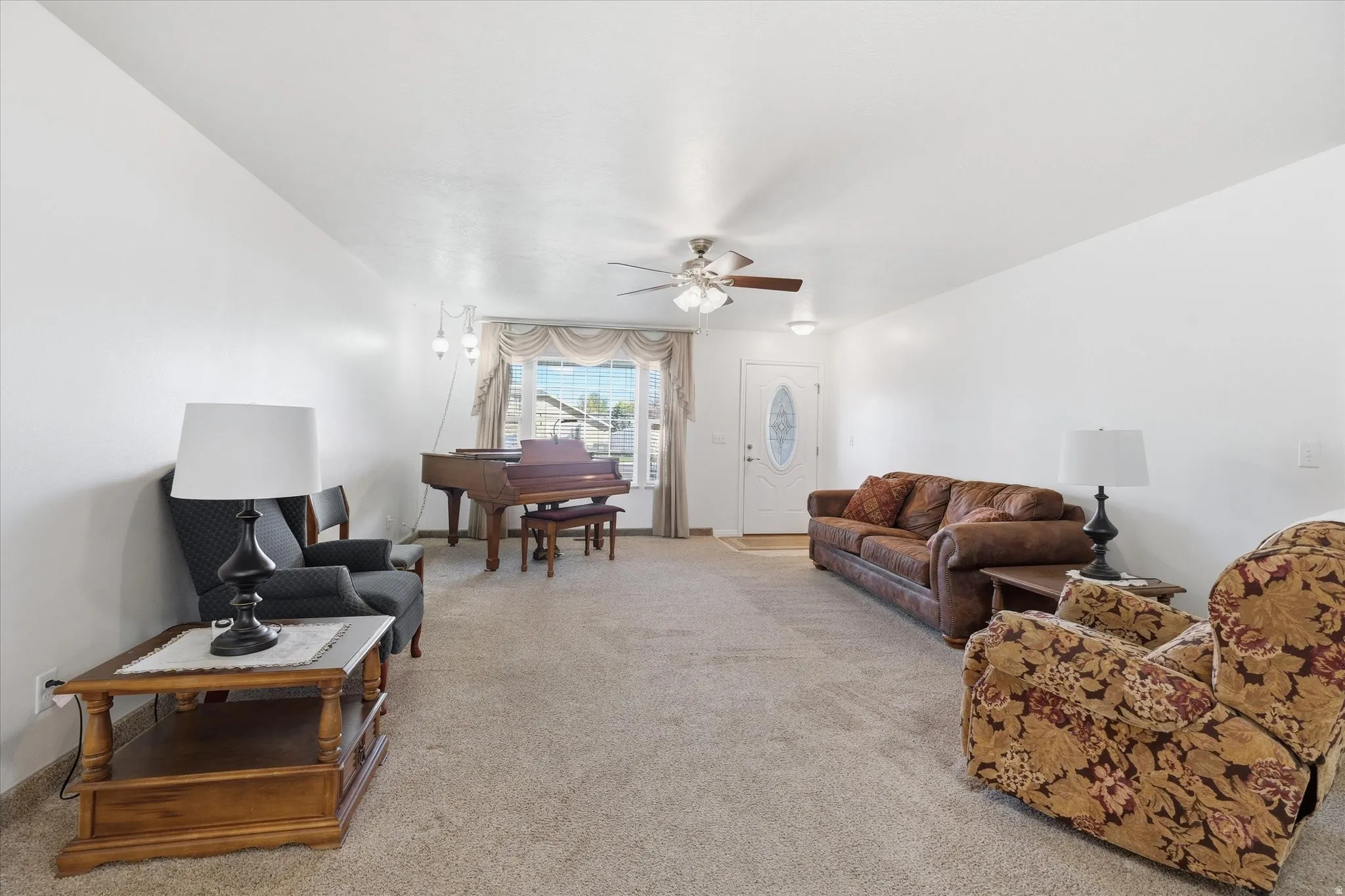 Living room featuring light colored carpet and a ceiling fan