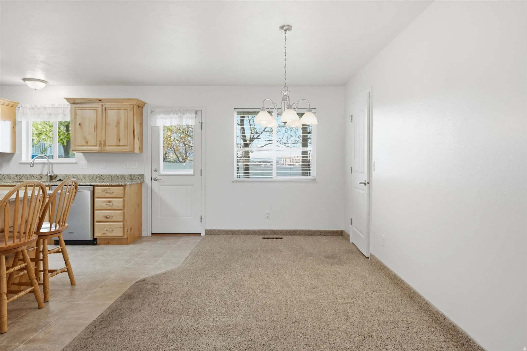 Dining room with light colored carpet, light tile patterned flooring, and hanging lights