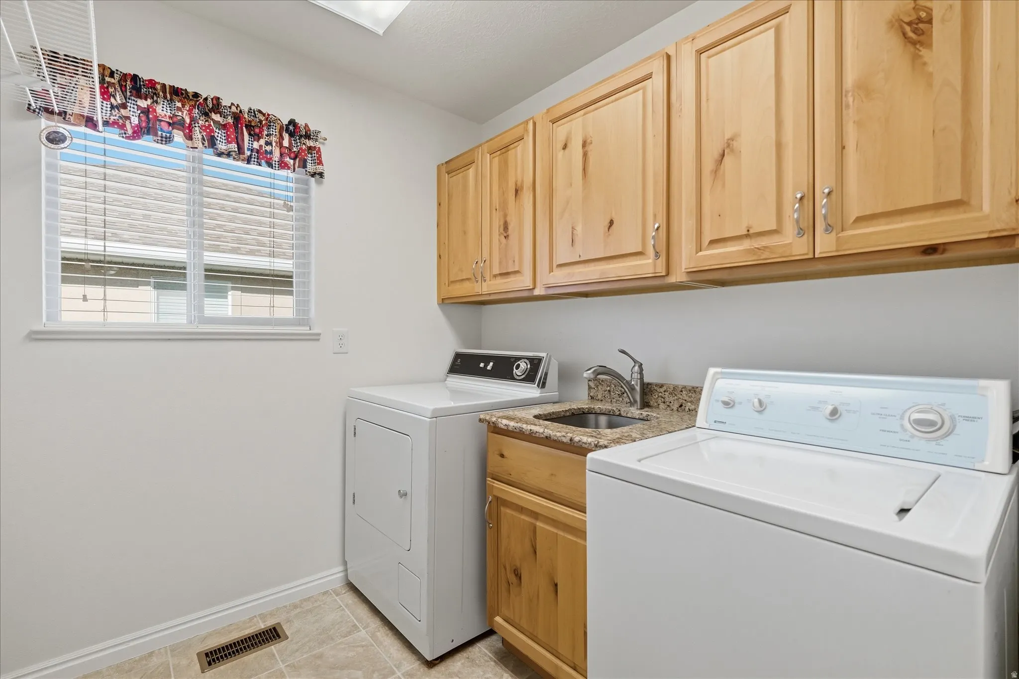Laundry area with cabinet space, separate washer and dryer, and light  patterned floors