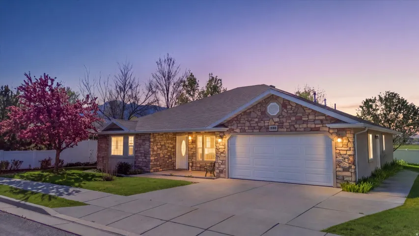 Ranch-style house featuring stone siding, an attached garage, driveway, and covered porch