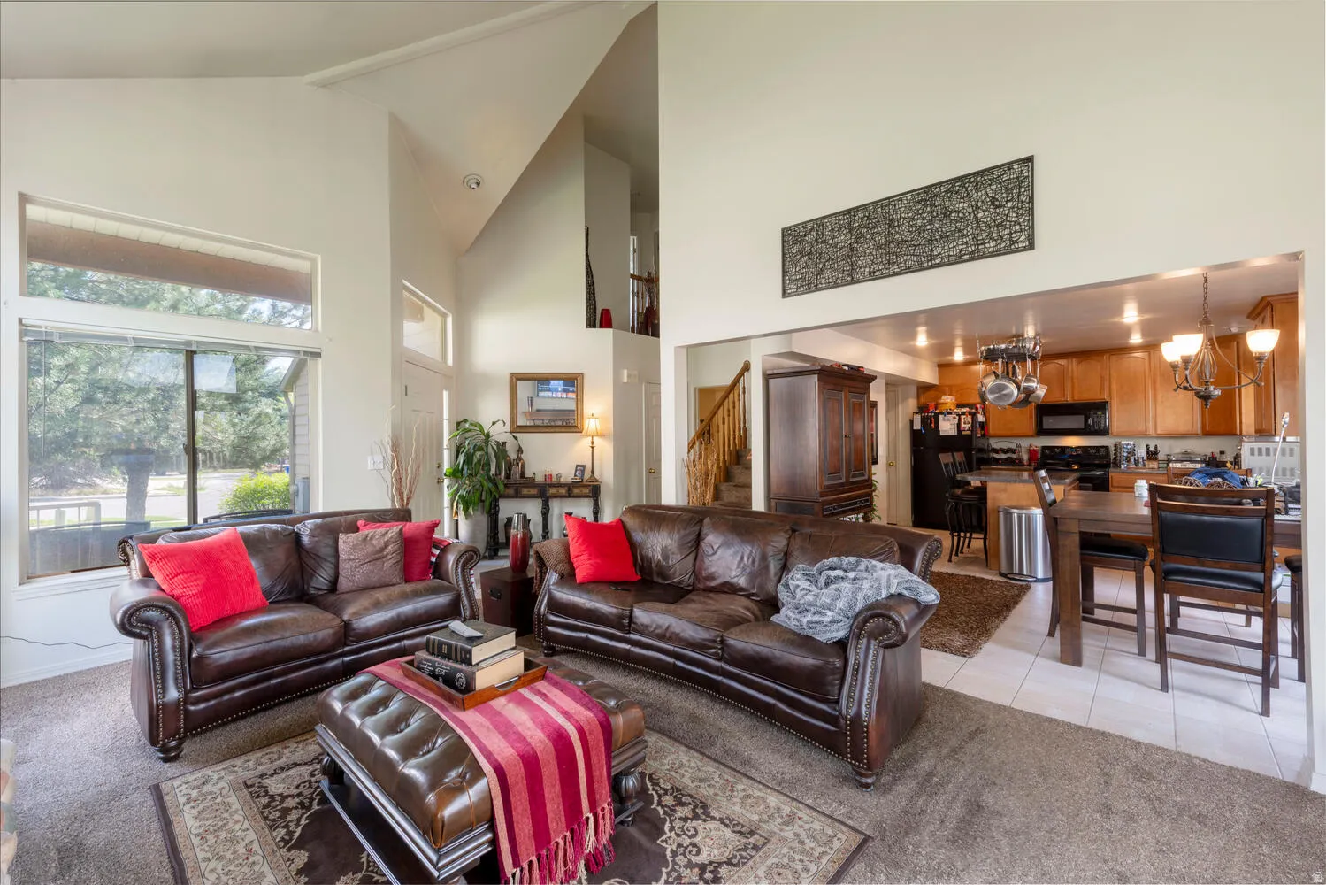 Living area with light colored carpet, lofted ceiling, light tile patterned flooring, and a chandelier