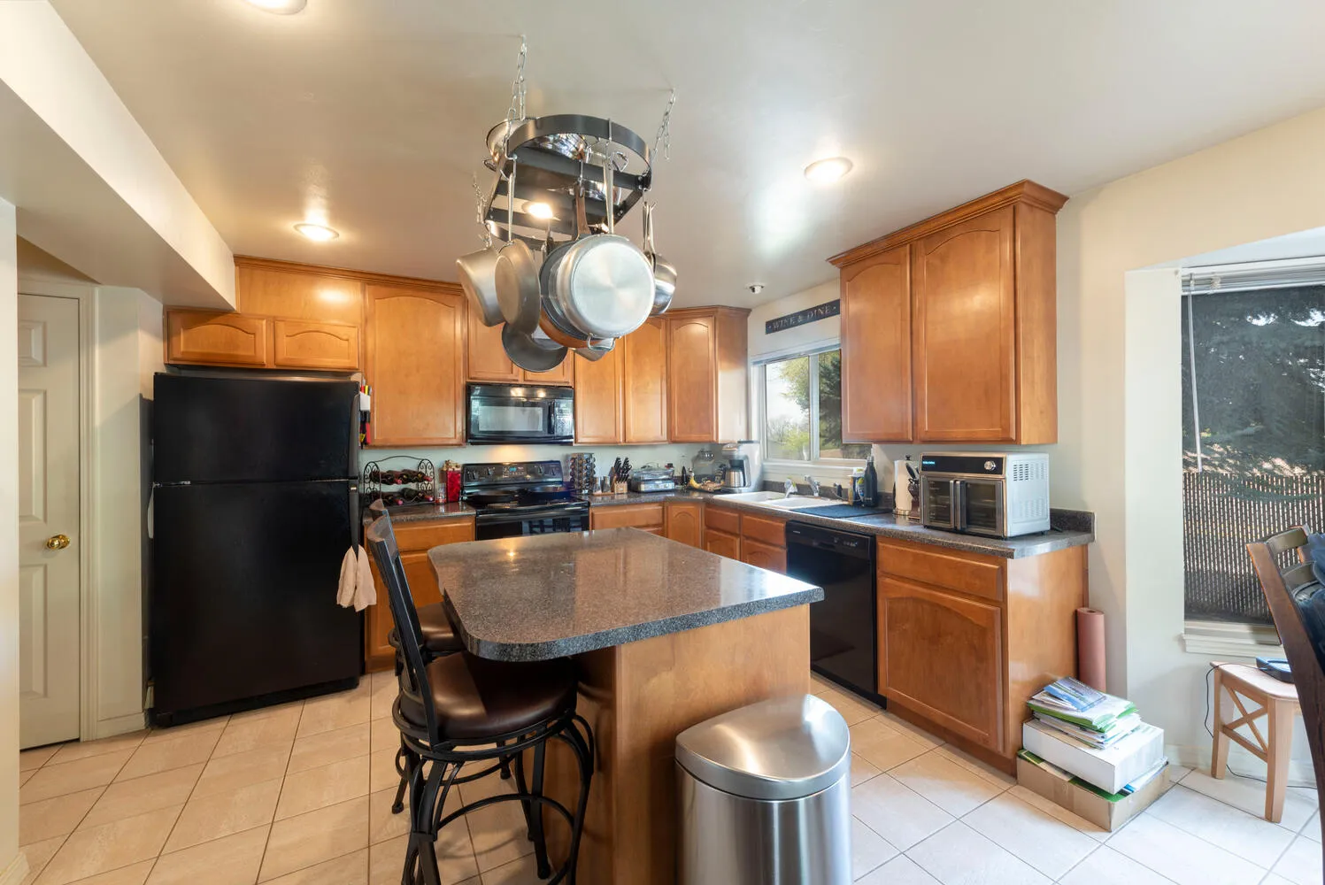 Kitchen with black appliances, dark countertops, a breakfast bar, a kitchen island, and wood finish cabinetry