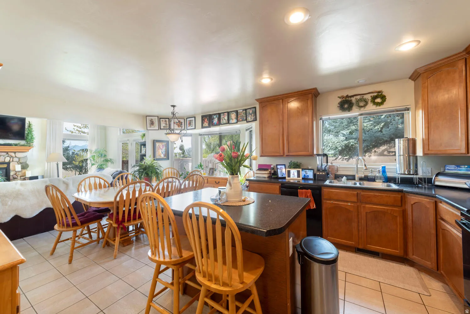 Kitchen with a kitchen island, dark countertops, wood finish cabinetry, open floor plan, and a kitchen breakfast bar