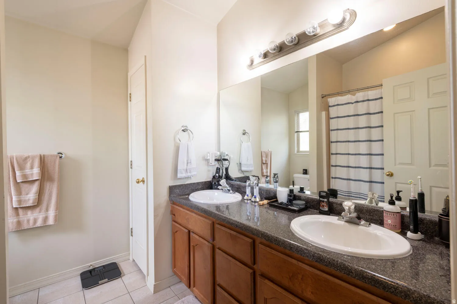 Full bath with double vanity, a shower/tub, and small storage nook closet