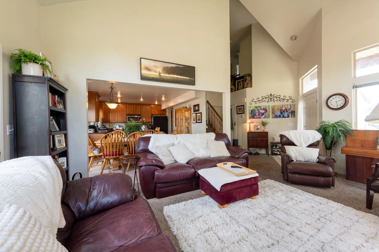 Carpeted living area with stairs and lofted ceiling