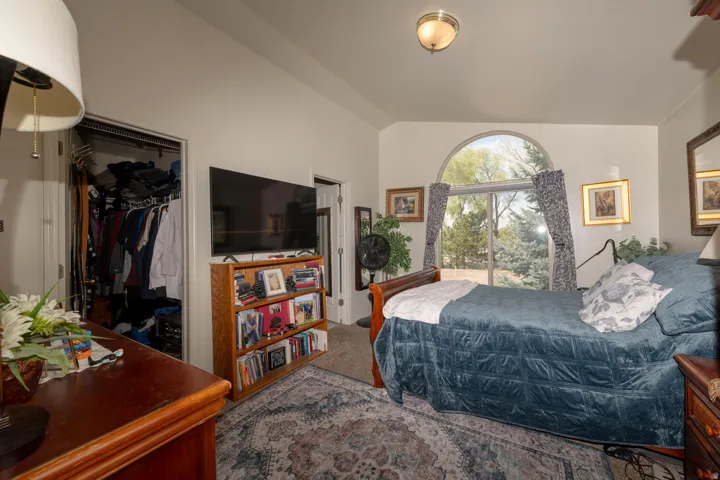 Carpeted primary ensuite bedroom featuring a spacious walk in closet and lofted ceiling