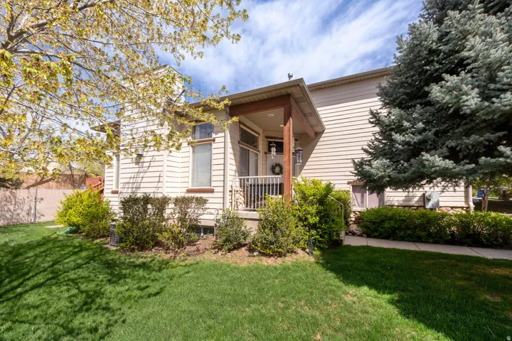 View of front door of 7456 (west side of duplex) with a front yard and a porch