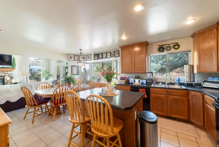 Kitchen with a kitchen island, dark countertops, wood finish cabinetry, open floor plan, and a kitchen breakfast bar