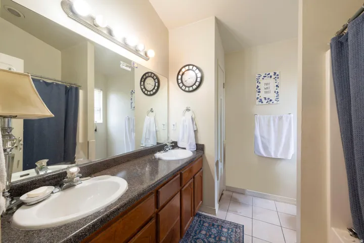 Full bath in primary bedroom featuring curtained shower/tub, double vanity