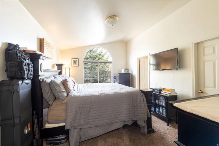 Carpeted bedroom featuring vaulted ceiling