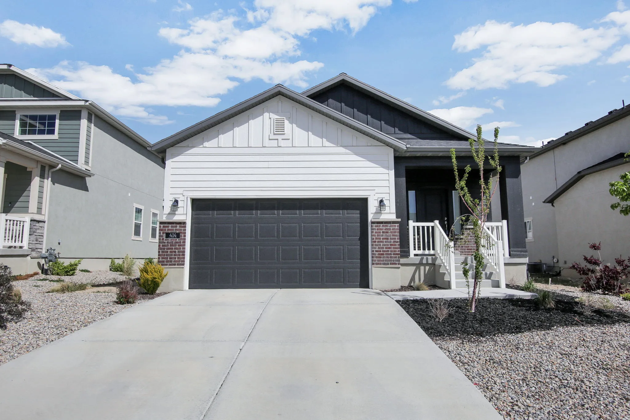 View of front of property featuring a porch, board and batten siding, a garage, concrete driveway, and brick siding