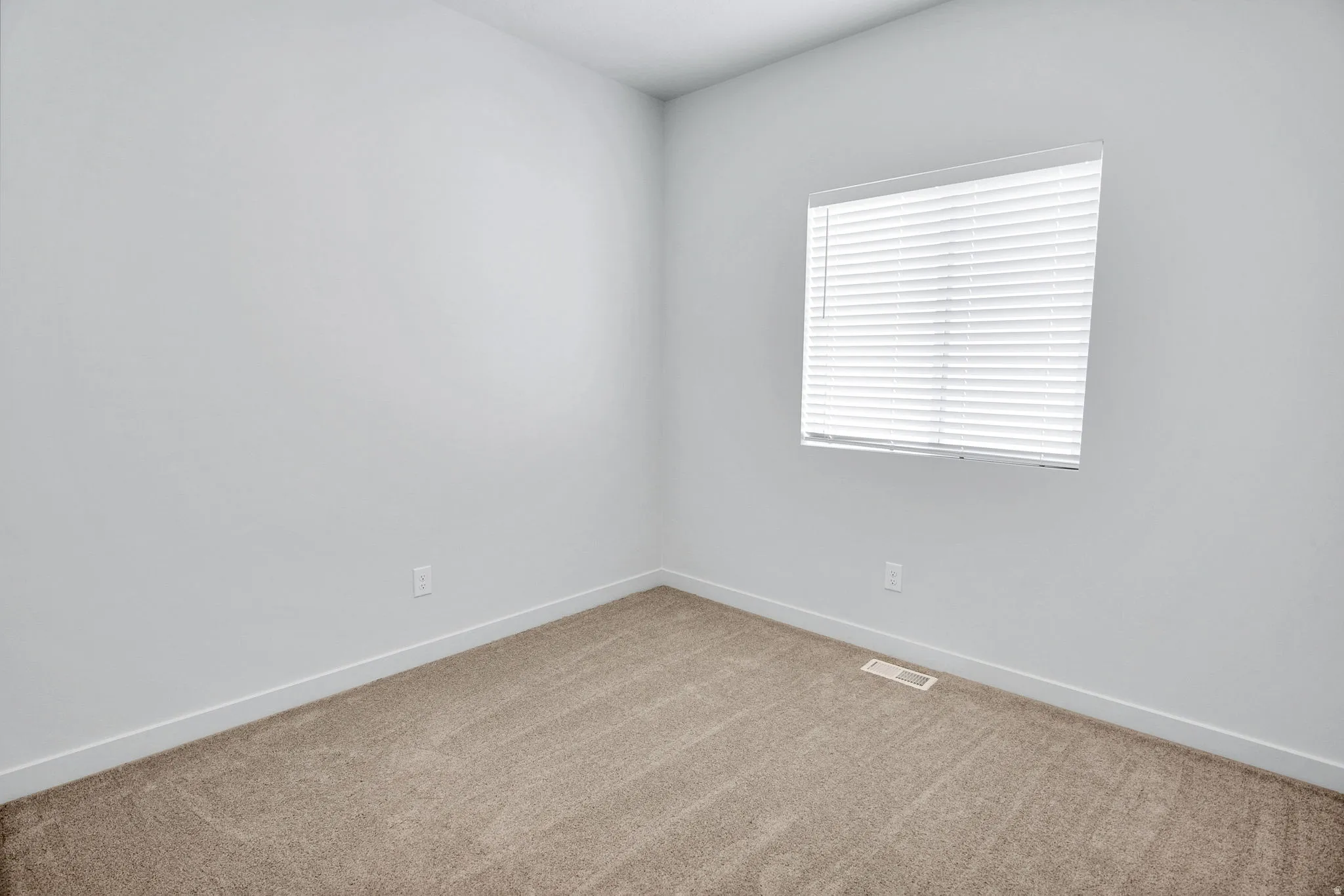 Spare room featuring light carpet and baseboards