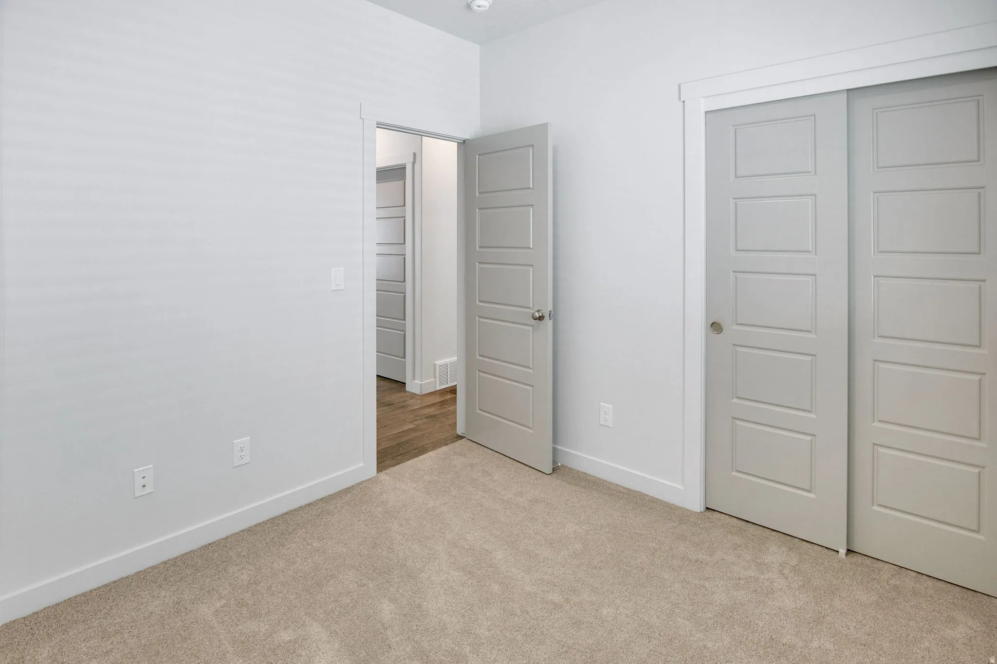 Unfurnished bedroom featuring a closet and light colored carpet