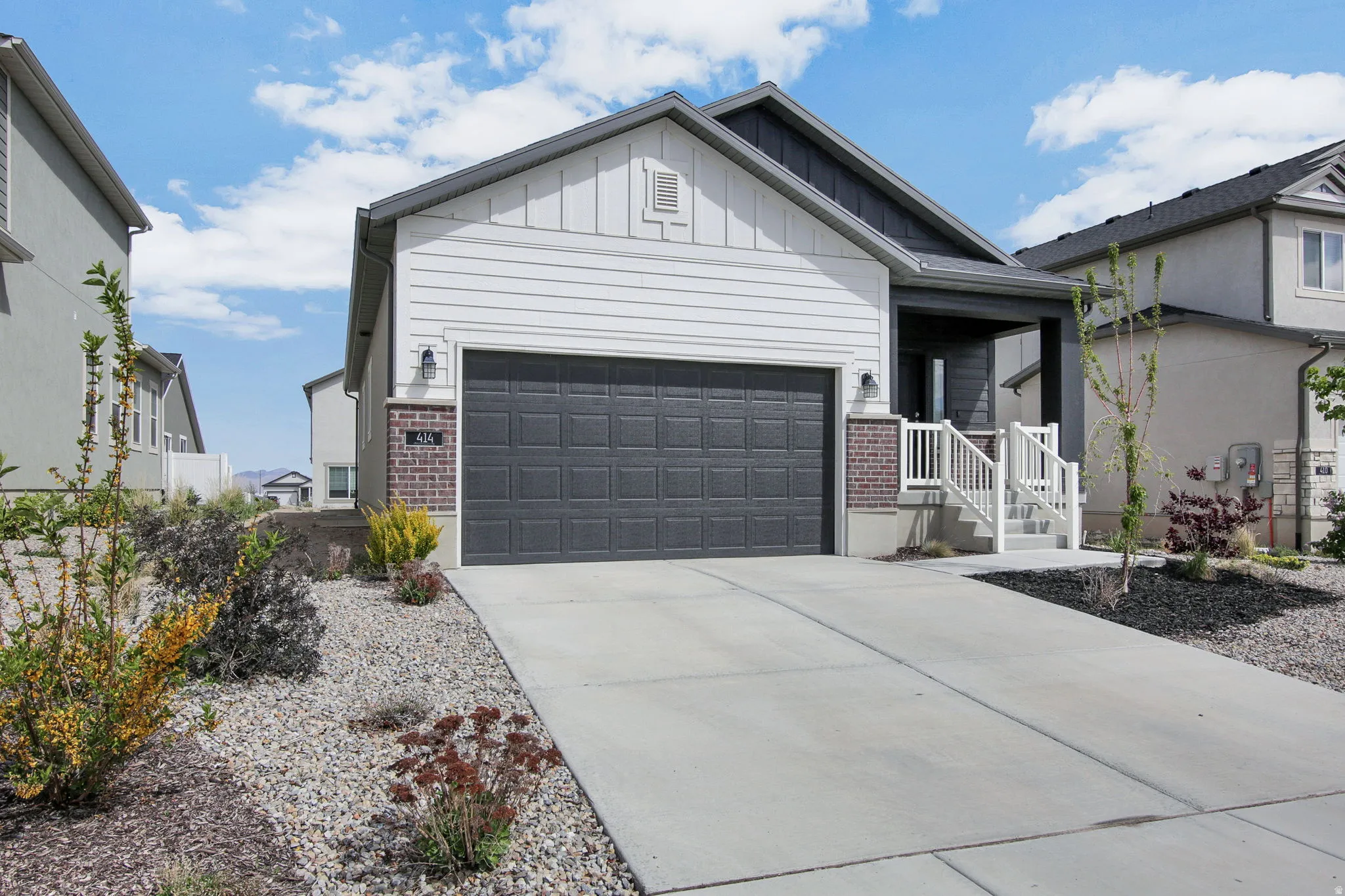 Ranch-style home featuring board and batten siding, brick siding, driveway, covered porch, and an attached garage