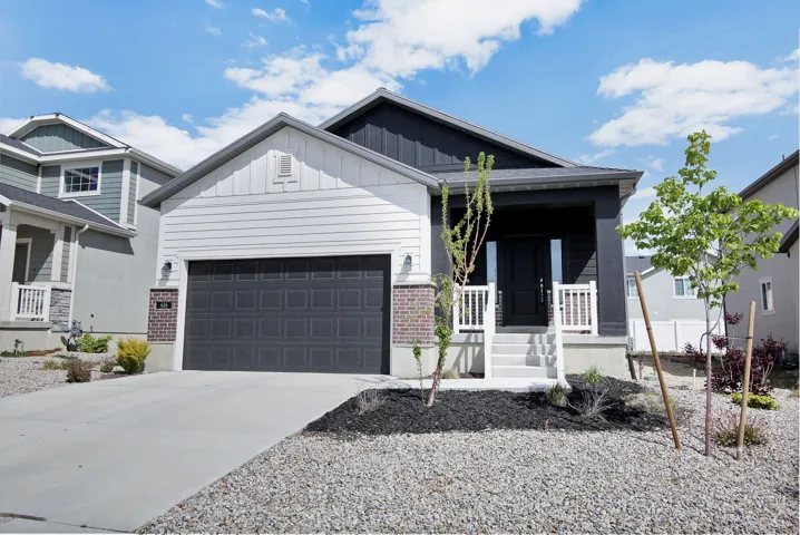 View of front facade with covered porch, driveway, board and batten siding, a garage, and brick siding