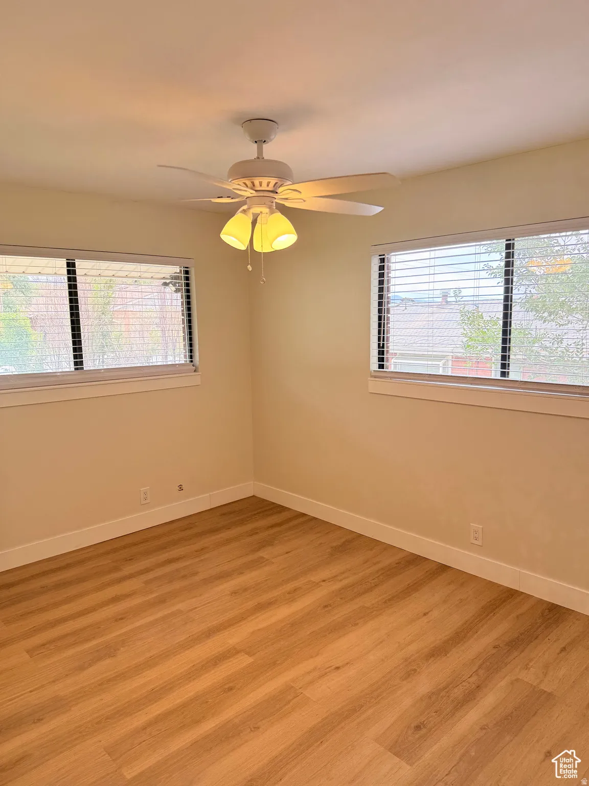 Spare room with healthy amount of natural light, wood finished floors, and a ceiling fan