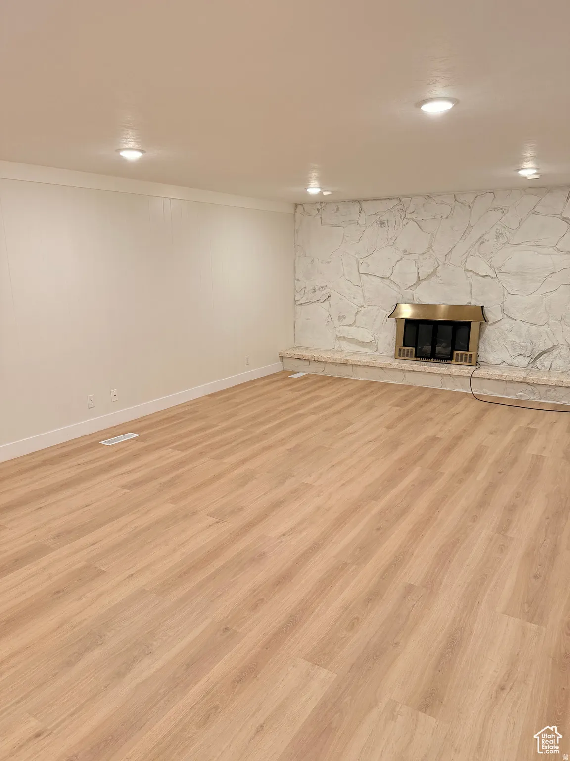 Finished below grade area featuring a fireplace, light wood-style floors, and crown molding