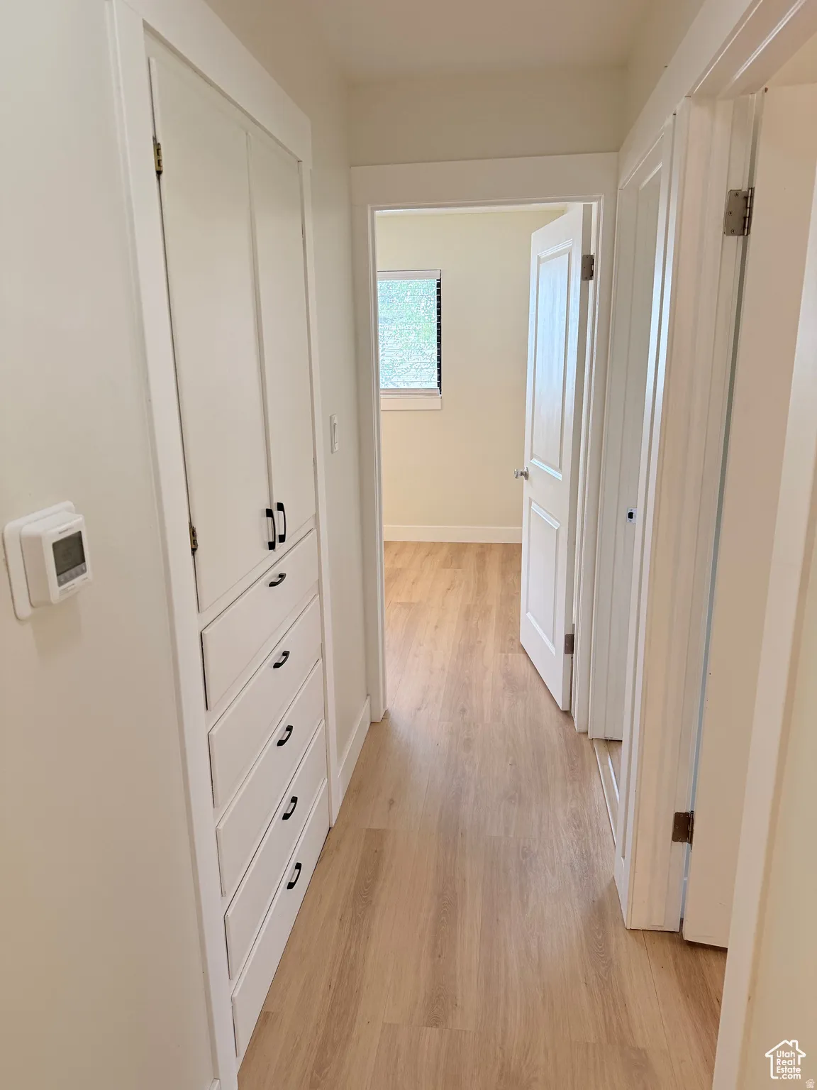 Corridor featuring light wood-style flooring and baseboards