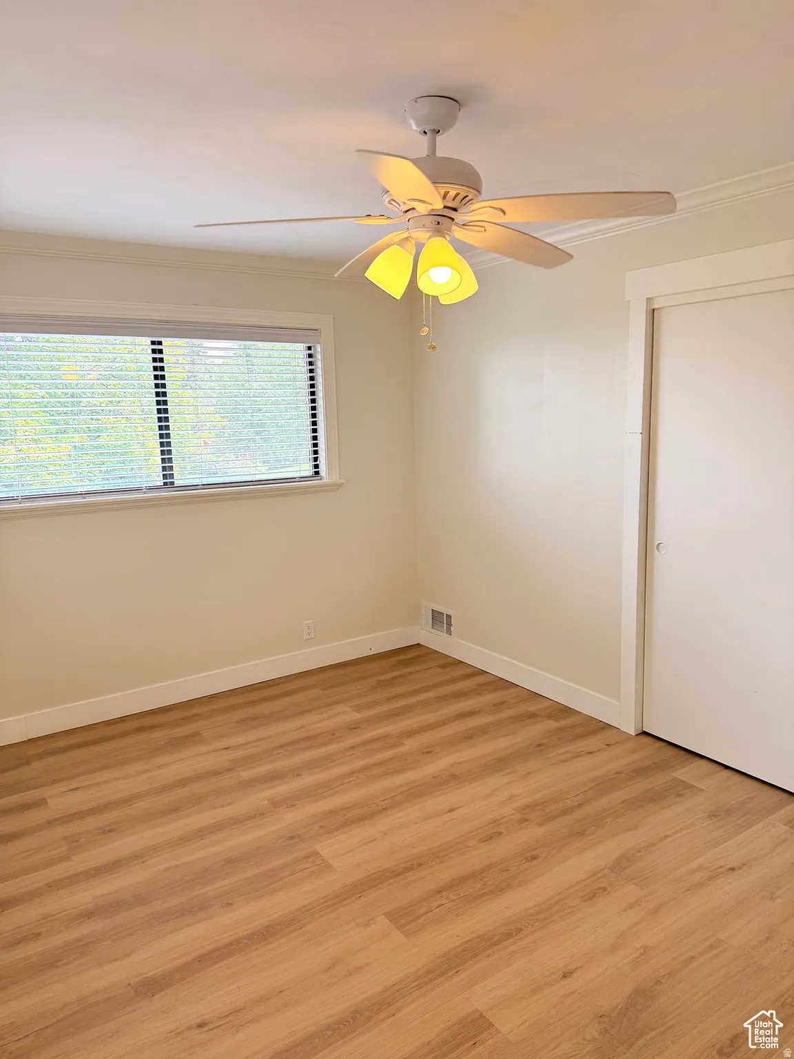 Unfurnished room featuring ornamental molding, light wood-type flooring, and ceiling fan