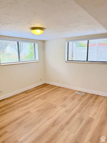 Spare room featuring light wood-type flooring and a textured ceiling