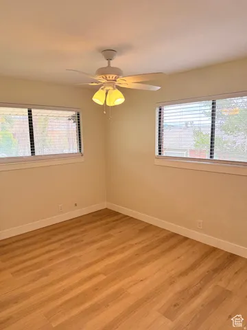 Spare room with healthy amount of natural light, wood finished floors, and a ceiling fan