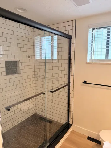 Full bath featuring a textured ceiling, a shower stall, and light wood-style floors