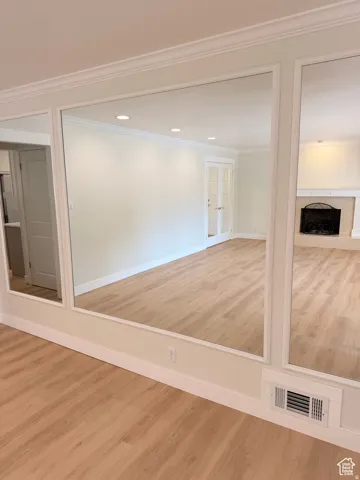 Empty room with light wood-type flooring, a fireplace, and crown molding