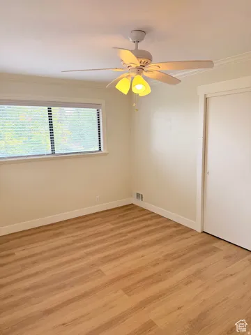 Unfurnished room featuring ornamental molding, light wood-type flooring, and ceiling fan