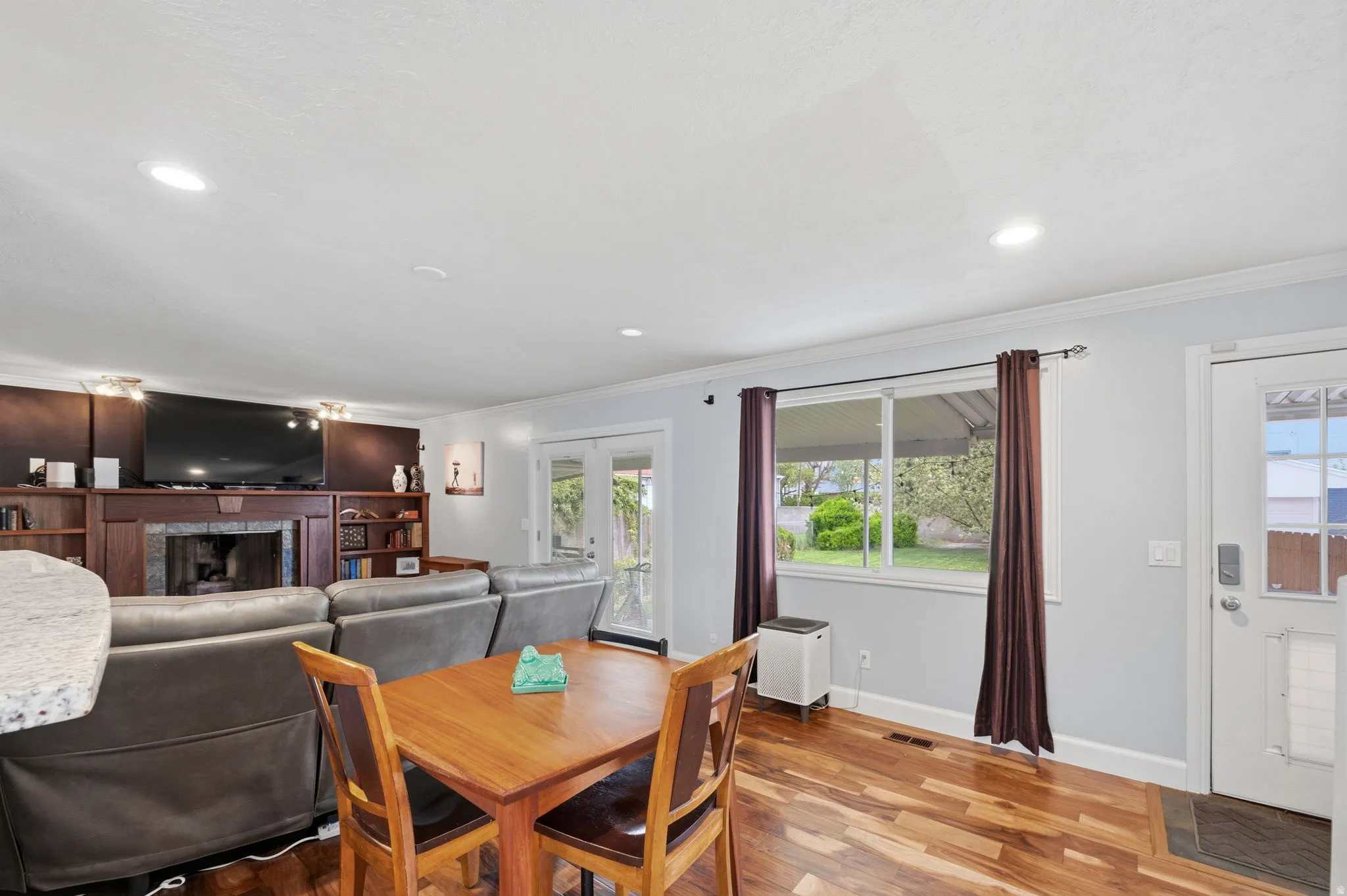 Dining room featuring wood finished floors, ornamental molding, a fireplace, recessed lighting, and french doors