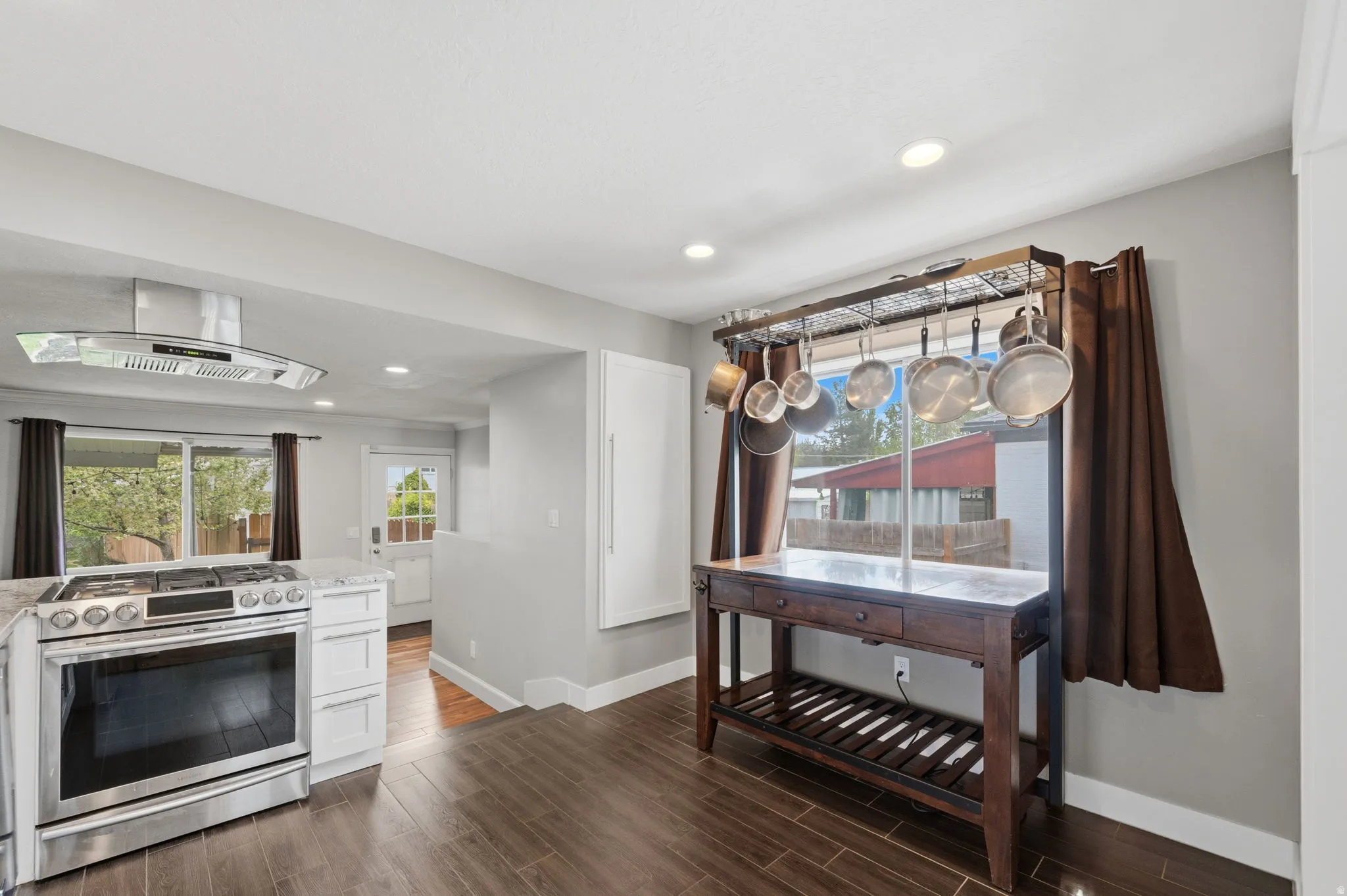 Kitchen featuring stainless steel range with gas stovetop, exhaust hood, wood finish floors, recessed lighting, and white cabinets